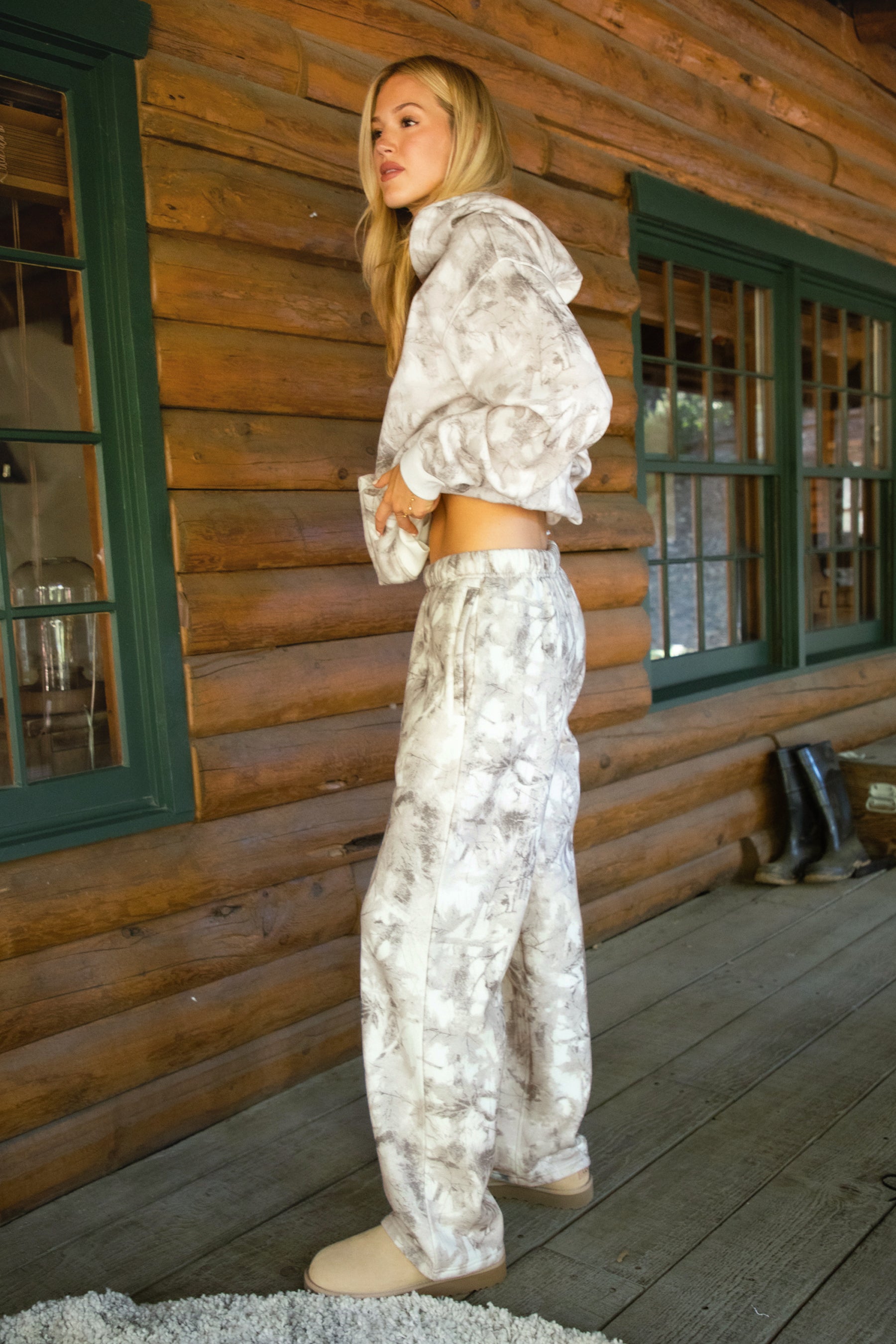 Women wearing TIC TOC AVERY Woodland Camo Wide Leg Sweatpants with elastic waistband, drawcord, in a soft Cloud Fleece fabric in a cabin