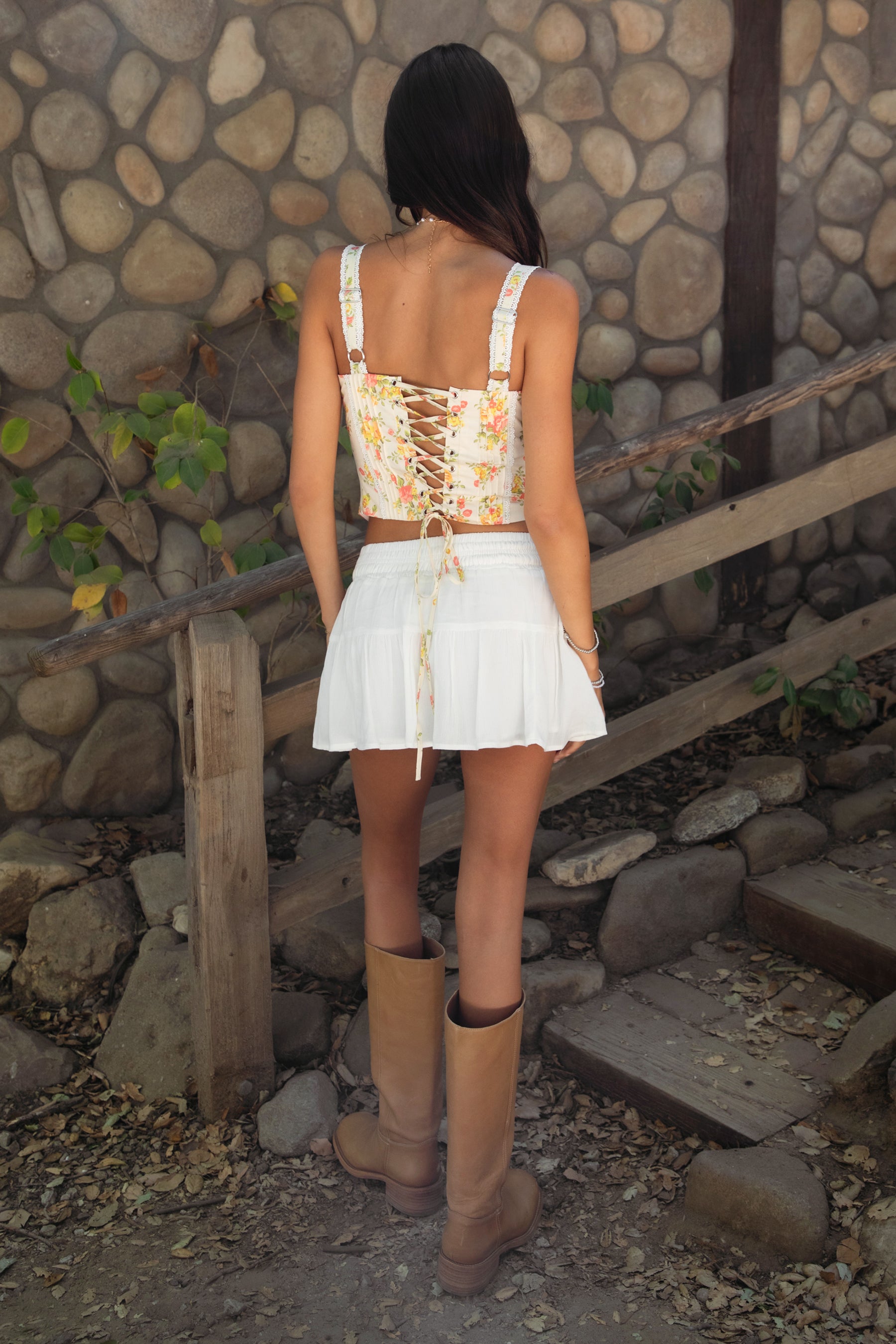Woman wearing YNES Crinkle Gauze Tiered Mini Skort With Short In White With A Floral Top and  tan boots