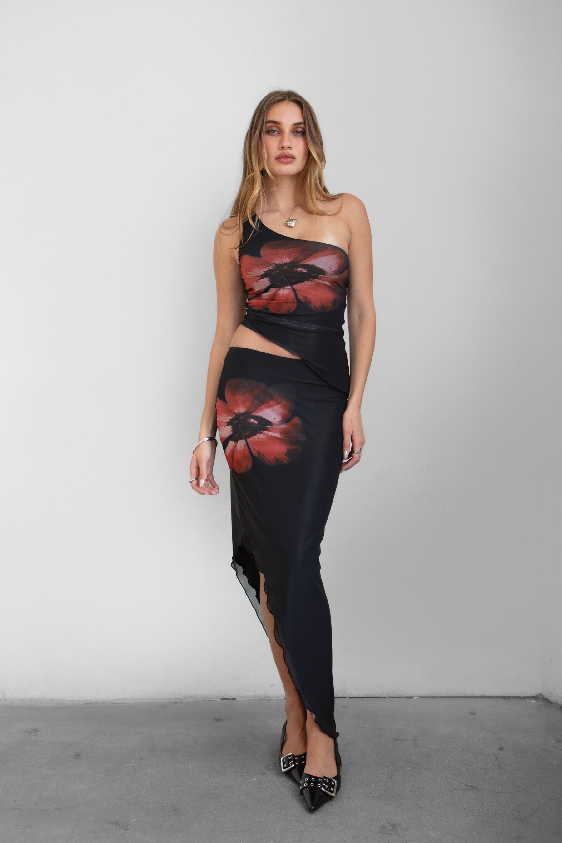 TIC TOC MUAH S Mesh Print Asymmetrical Skirt in Black and red with mid rise stretch waistband and angled hem.