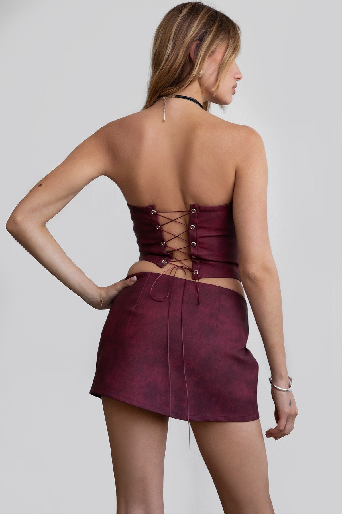 A woman wearing a red strapless corset top with embroidered details and a straight neckline, paired with a mini skirt.
