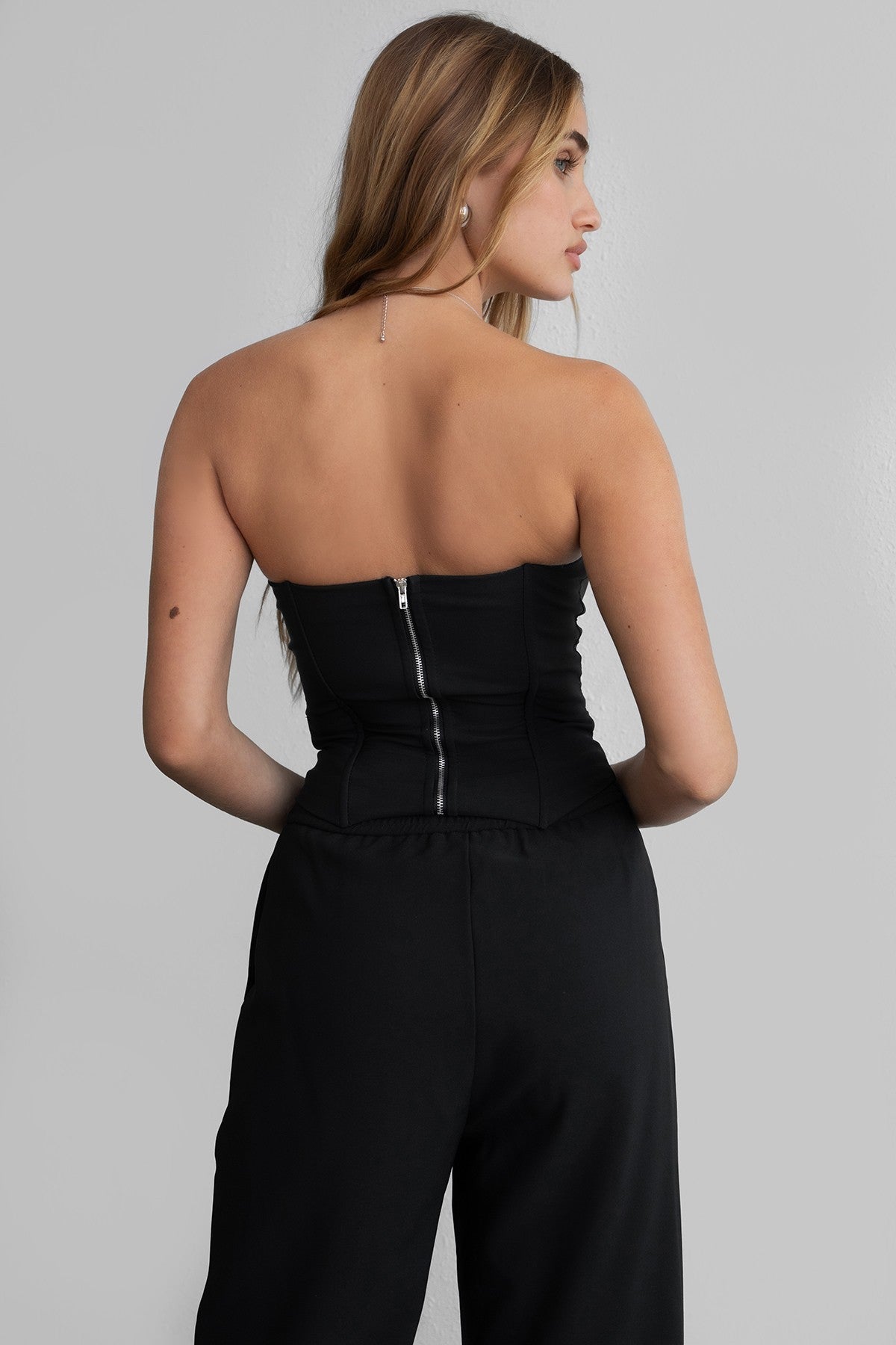TIC TOC KARMEN Strapless Corset Top in black with sheer front cutout, rhinestone bows, and curved hem.