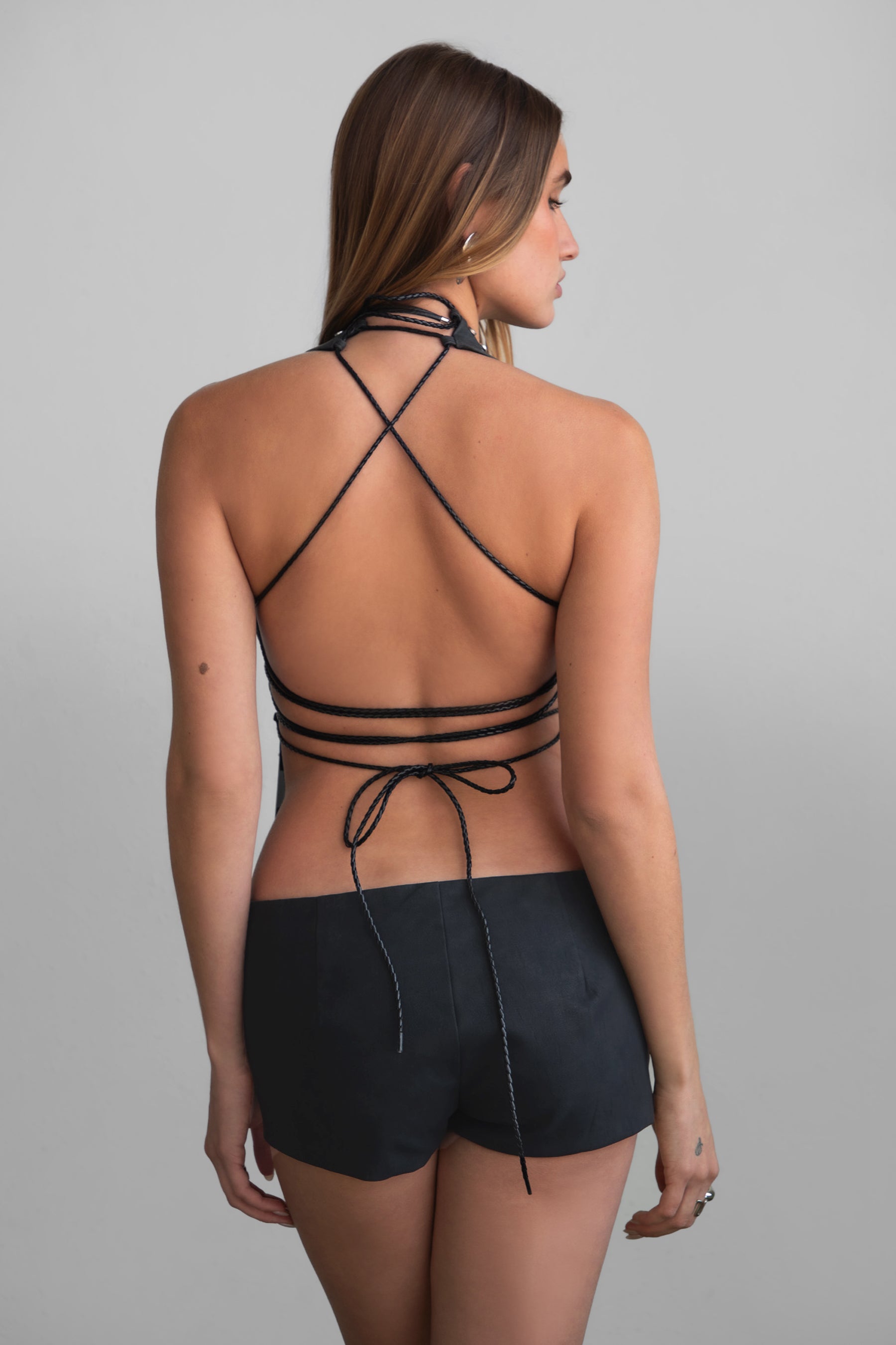 TIC TOC LYLA Distressed Leather Halter Top in black with lace-up open torso, studded detail, and open back design.