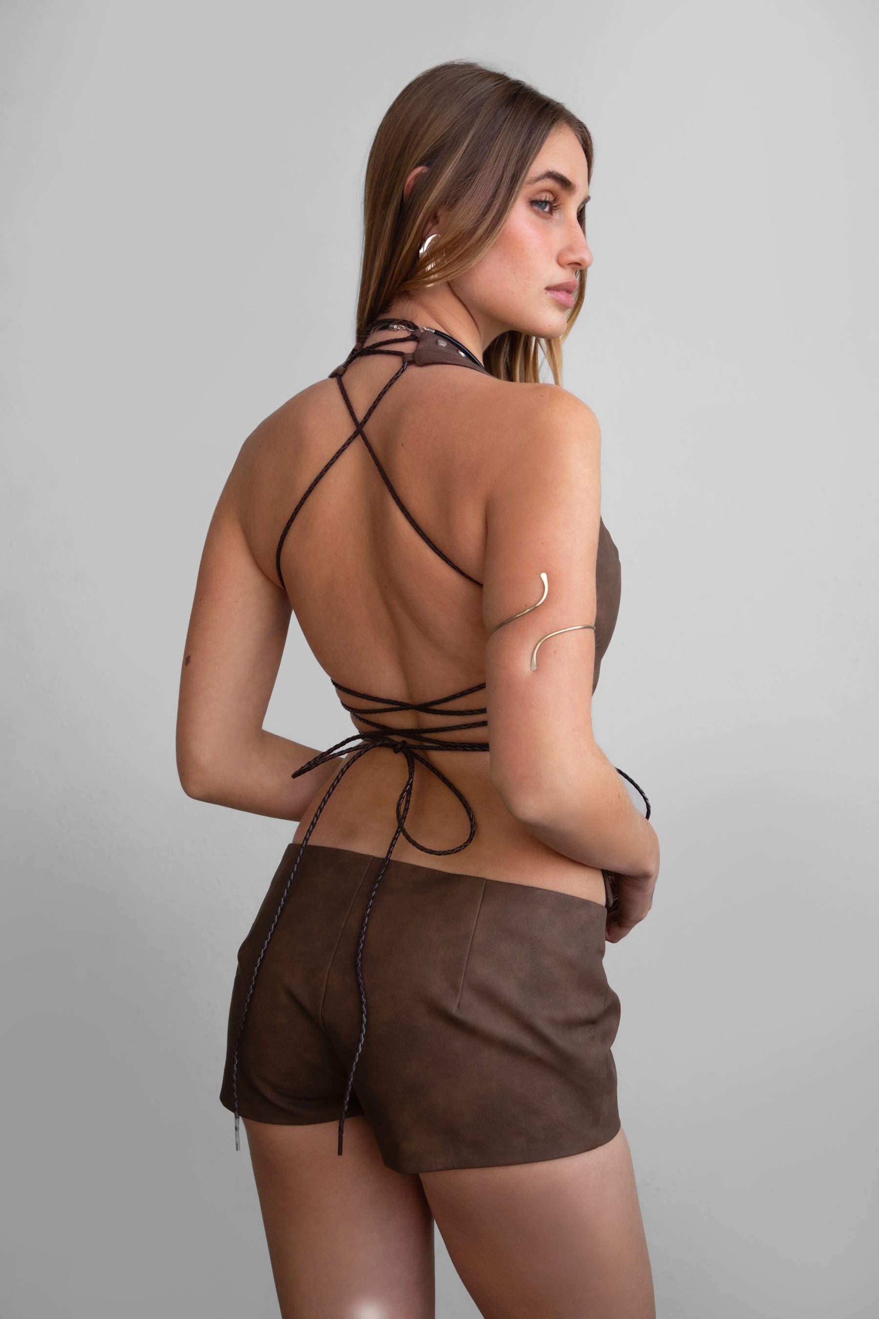 TIC TOC LYLA Distressed Leather Halter Top in Brown with lace-up open torso, studded detail, and open back design.