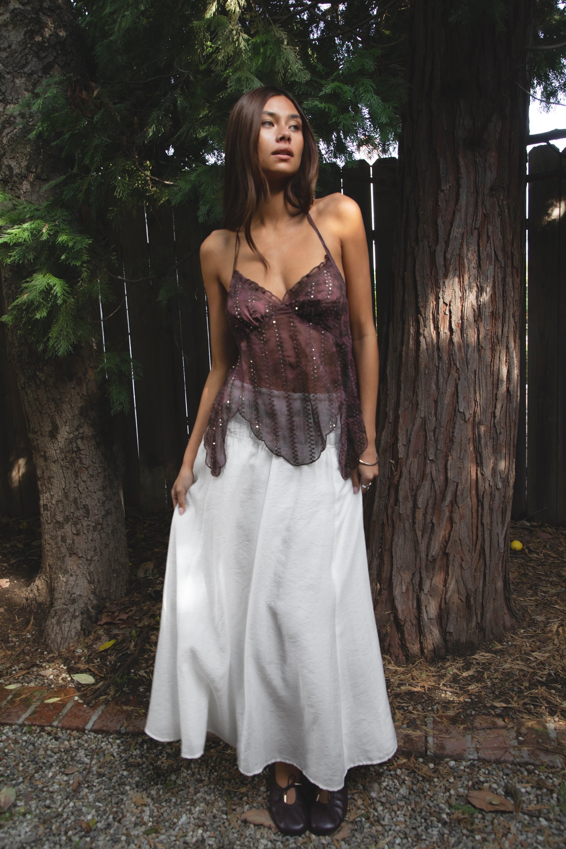 Woman wearing TIC TOC TA31758 ISOLA scalloped sequin chiffon open back halter top featuring a ruffle-trim V-neckline, delicate sequin embroidered chiffon, adjustable self-tie halter neck, open back tie closure, and a scalloped handkerchief hem, styled for a romantic vacation and elevated western evening look.