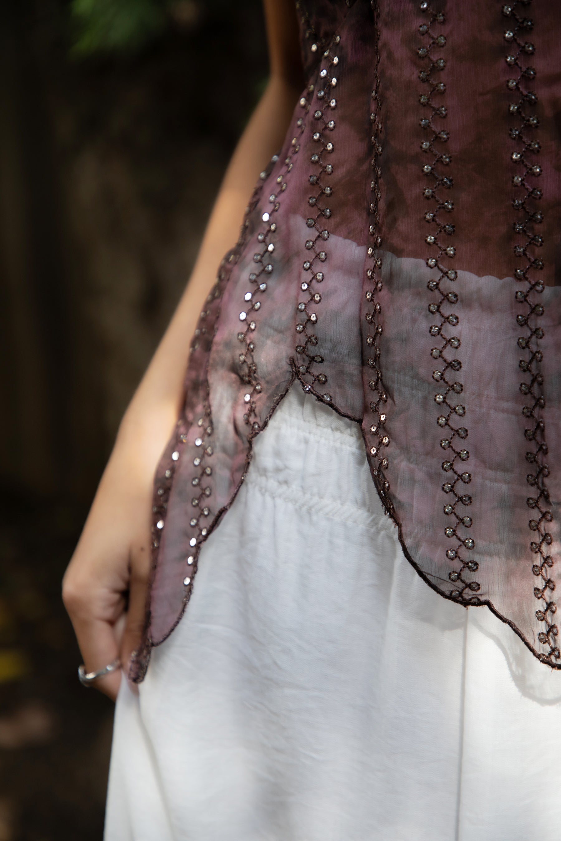 Woman wearing TIC TOC TA31758 ISOLA scalloped sequin chiffon open back halter top featuring a ruffle-trim V-neckline, delicate sequin embroidered chiffon, adjustable self-tie halter neck, open back tie closure, and a scalloped handkerchief hem, styled for a romantic vacation and elevated western evening look.