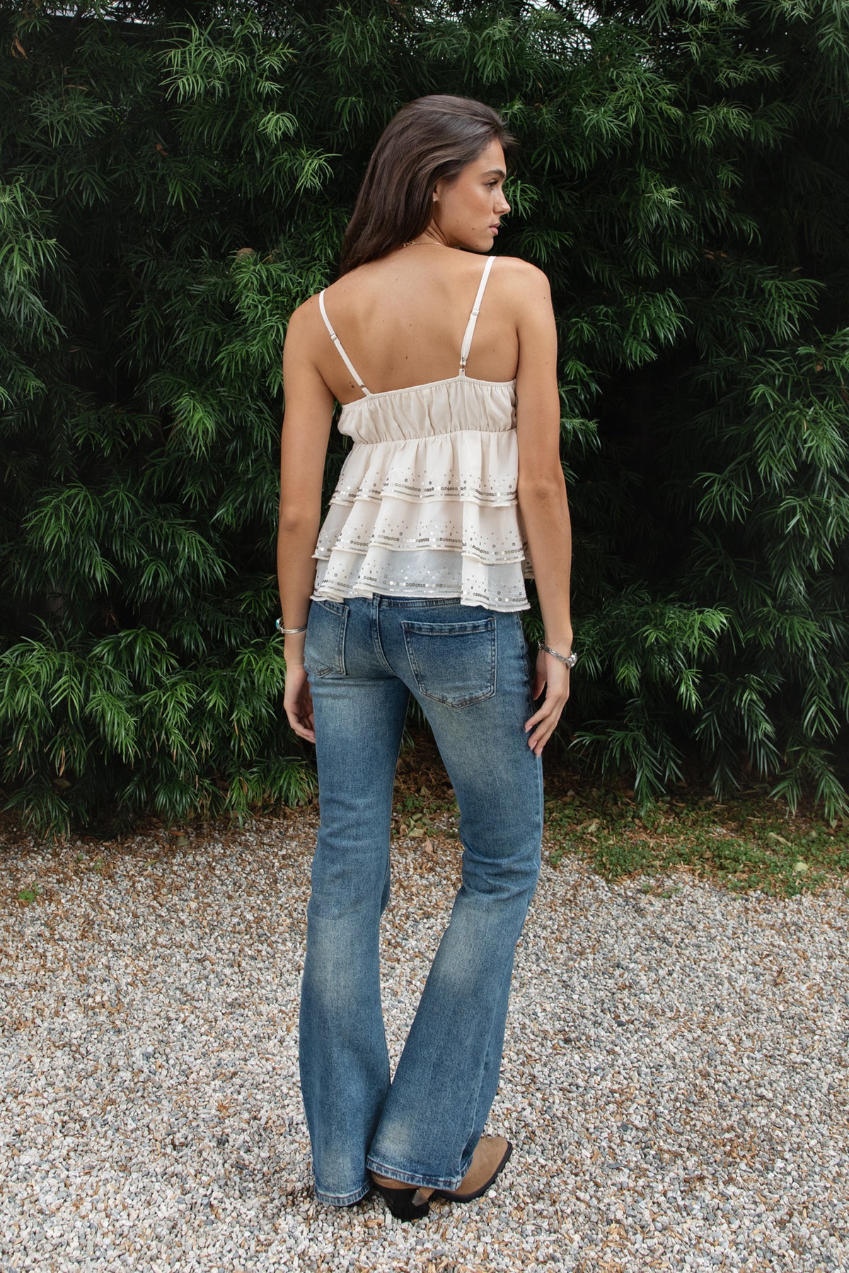 Woman wearing SERAFINA sequin embroidered tiered ruffle cami top featuring lightweight chiffon fabric, deep V neckline with soft triangle bust, adjustable spaghetti shoulder straps, gathered empire waist silhouette, three tiered flowing chiffon ruffles with delicate sequin embroidery, elasticized back, and soft stretch woven lining.