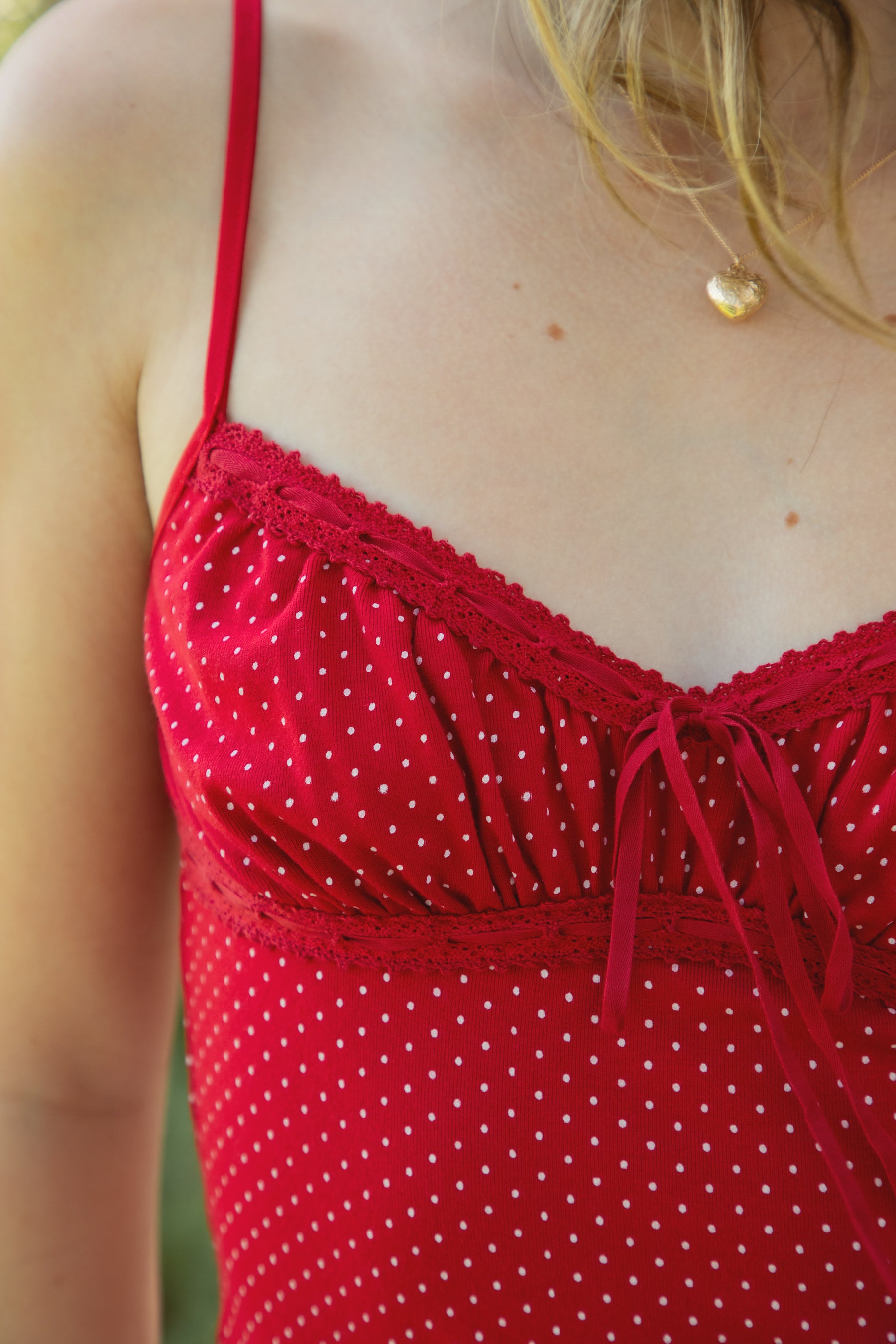 Woman wearing LOTTIE polka dot print lace contrast jersey tank featuring a delicate polka dot print, V-neckline with self-tie bow detail, lace trim along the neckline and under bust, adjustable thin straps, and a soft stretch jersey body-skimming silhouette.