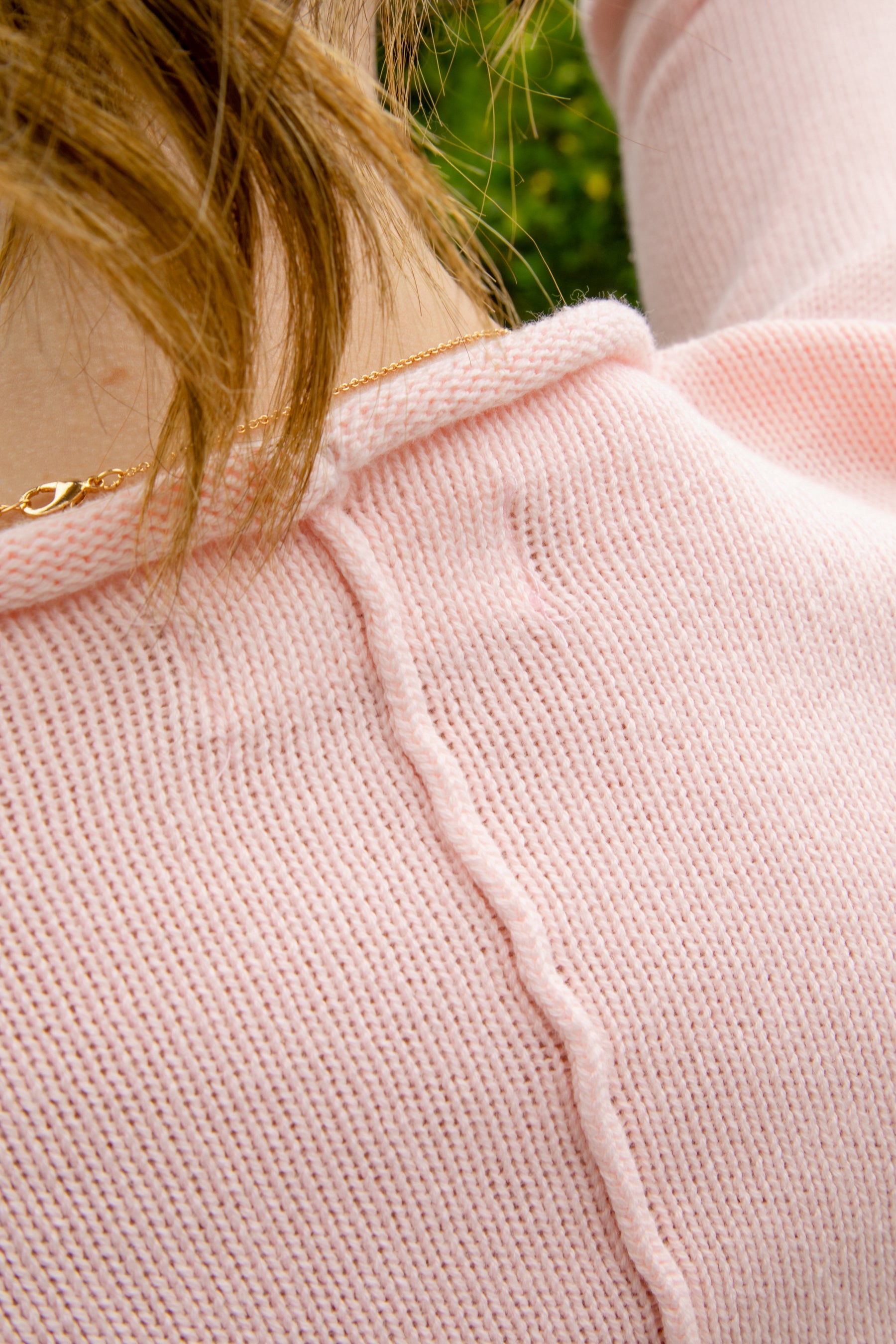 Woman wearing LUMEE rolled neck long sleeve knit sweater featuring a minimal rolled neckline, soft cotton knit fabric, long sleeves with ribbed cuffs and hem, center back seam detail, and a relaxed cropped fit for easy everyday layering.