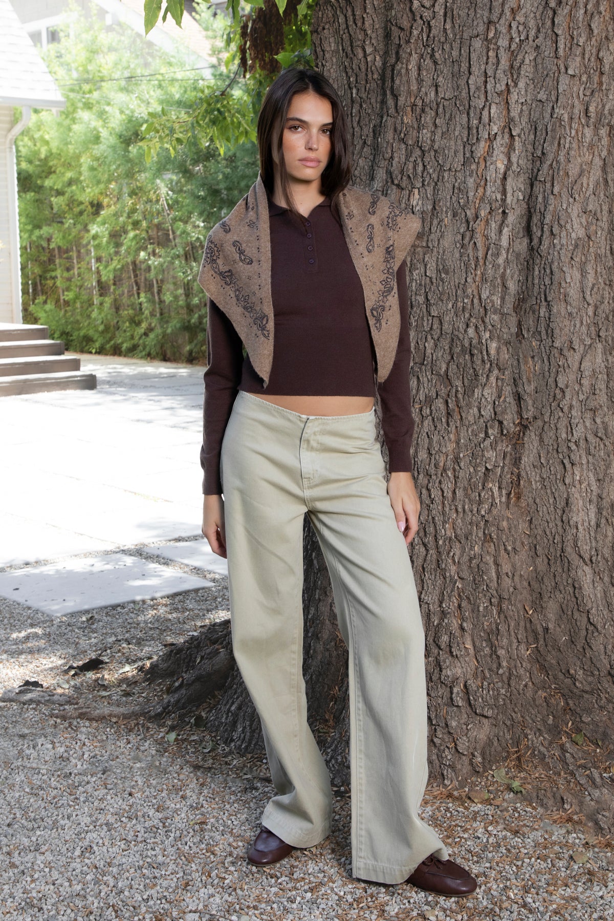 Woman wearing ESSIE collared button front knit top featuring soft sweater knit fabric with a smooth feel, classic polo collar, four button front closure, slim fit silhouette, long sleeves with fitted ribbed cuffs, subtle ribbed knit detailing at the waist, wide ribbed hem, and slightly cropped length with a clean finish.