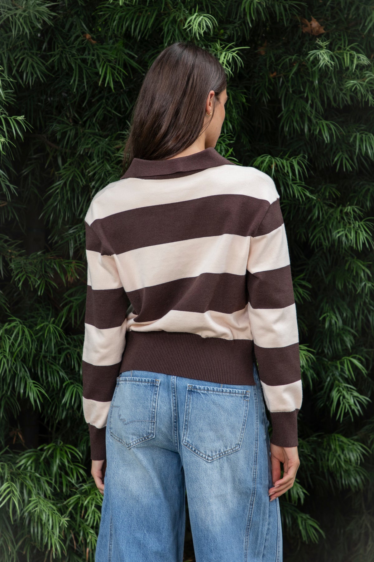 Woman wearing PRESCOTT striped collared classic preppy sweater featuring soft sweater knit fabric, bold contrast stripes, polo inspired collar with open V neckline, wide horizontal stripe design, relaxed dropped shoulder silhouette, long sleeves with contrast ribbed cuffs, ribbed hem, and subtle side slits.