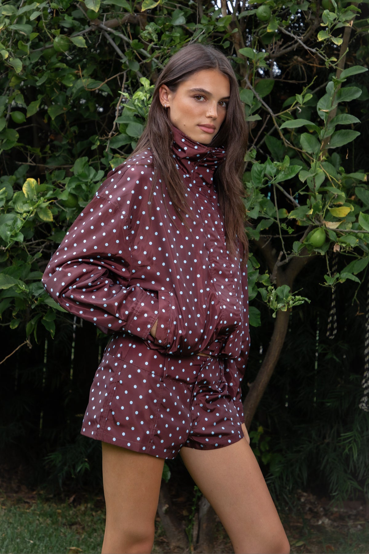 Woman wearing CLEMENTINE embroidered lace up halter mini dress featuring structured stretch fabric, fitted bodycon silhouette, straight neckline with adjustable halter tie straps, floral embroidery with western inspired details, deep center front lace up design with metal eyelets, gold tone stud embellishments along the neckline and hem, corset inspired contoured seaming, exposed back, and short mini length.