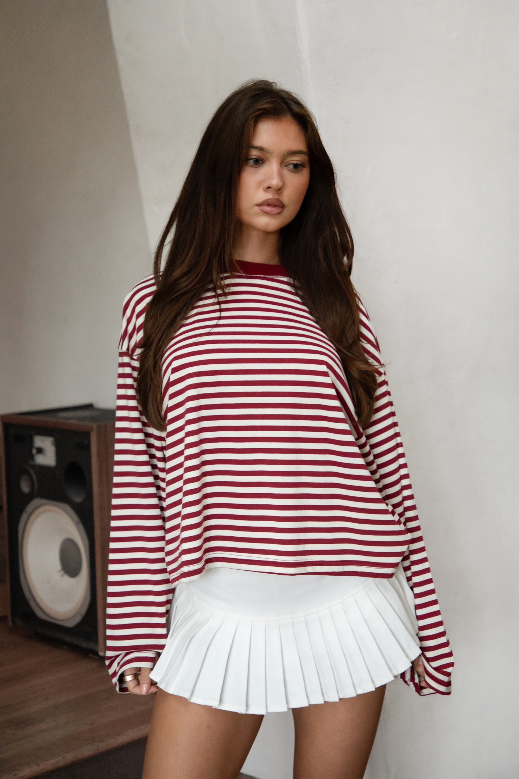 Woman wearing TIC TOC TH31849 MARLOWE striped long sleeve top with a classic crew neckline, relaxed semi-oversized fit, easy drop shoulders, and soft horizontal stripes paired with dark denim jeans in a casual outdoor street setting.
