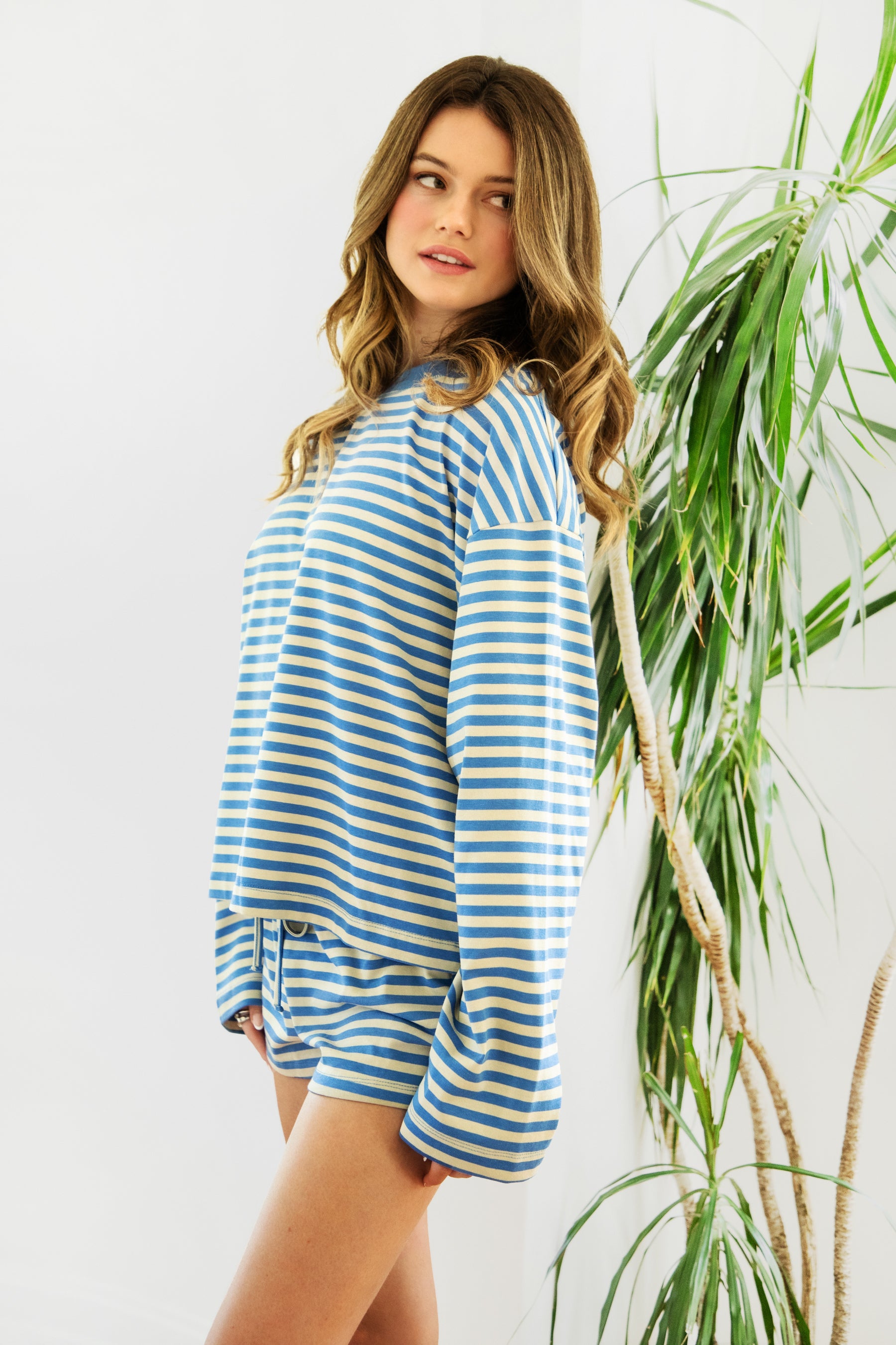 Woman wearing TIC TOC TH31849 MARLOWE striped long sleeve top with a classic crew neckline, relaxed semi-oversized fit, easy drop shoulders, and soft horizontal stripes paired with dark denim jeans in a casual outdoor street setting.