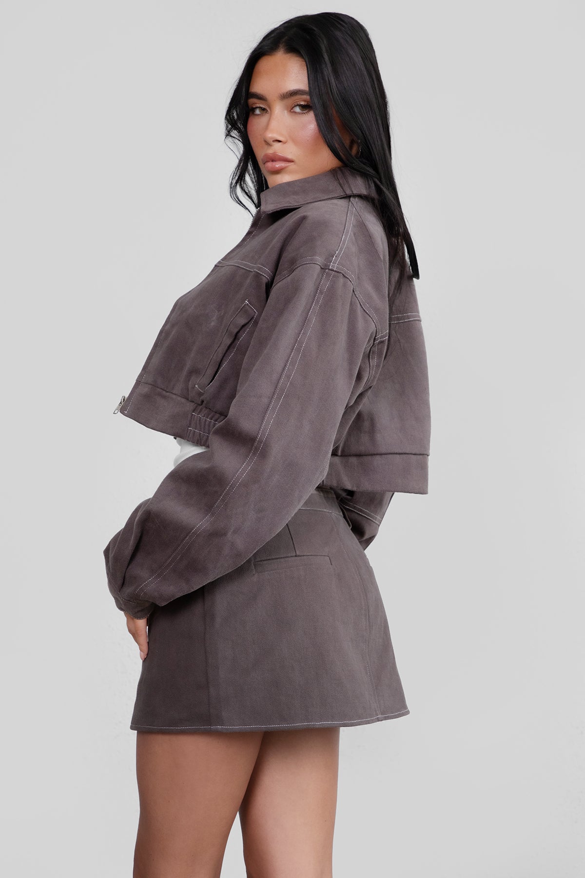 Woman wearing a gray jacket and skirt set on a white background