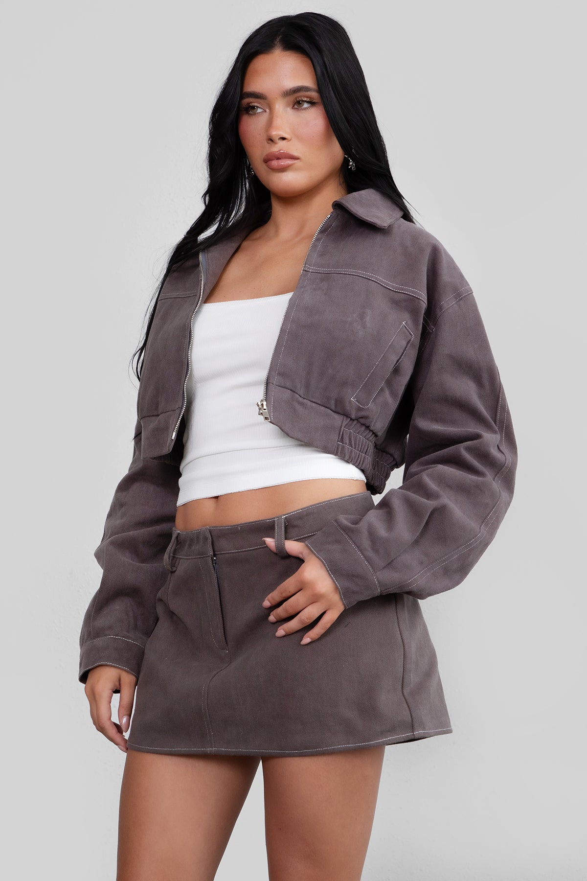 Woman wearing a gray jacket and skirt set on a plain background