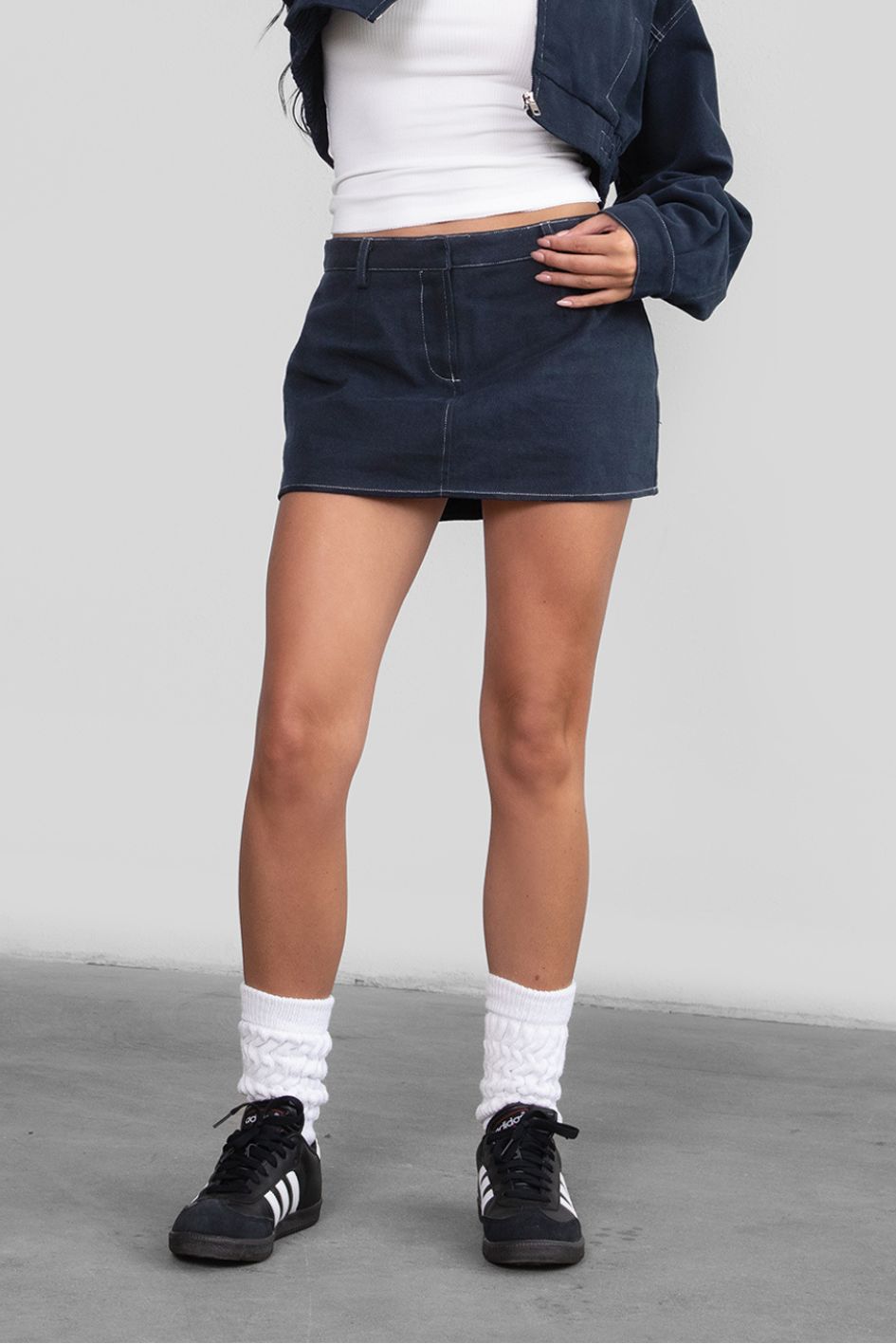 Person wearing a navy denim skirt with a plain background