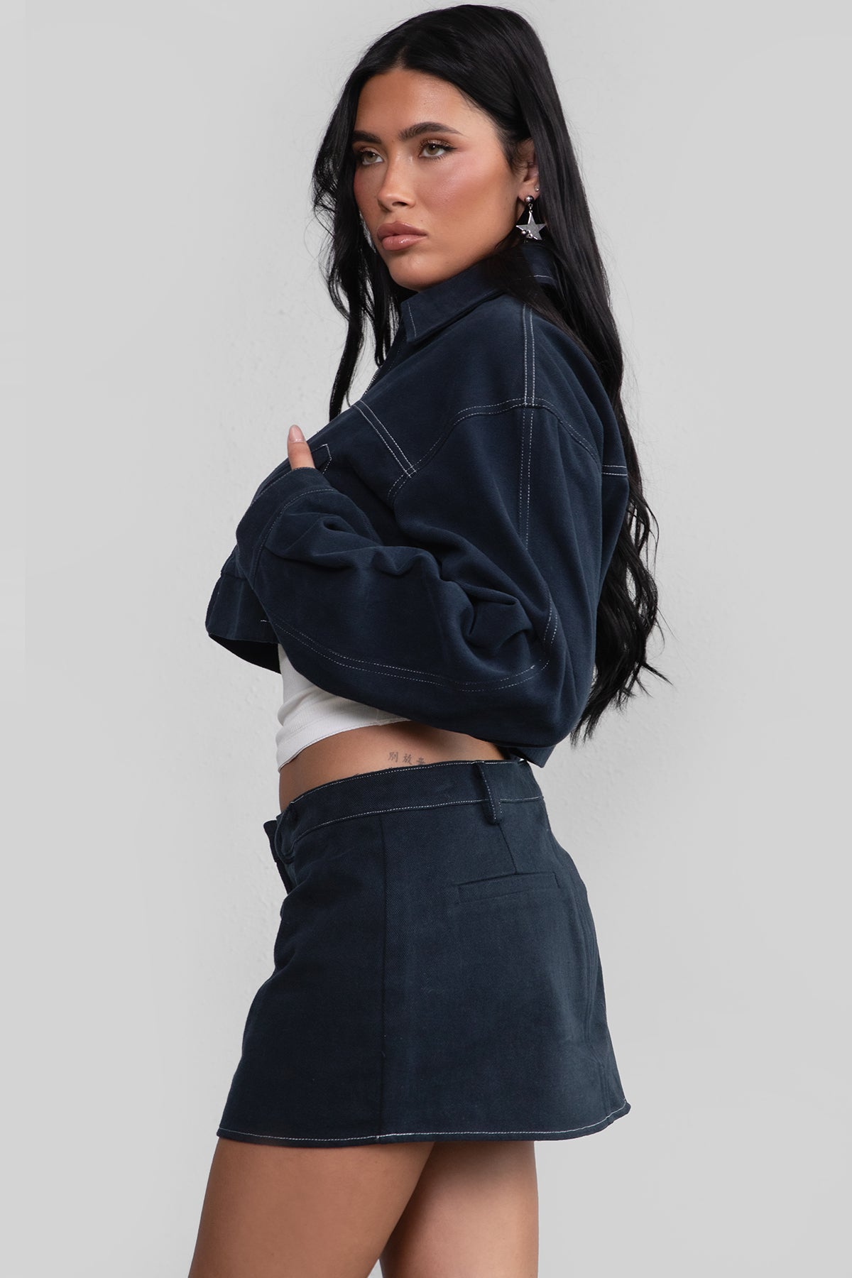 Woman wearing a navy jacket and skirt on a plain background