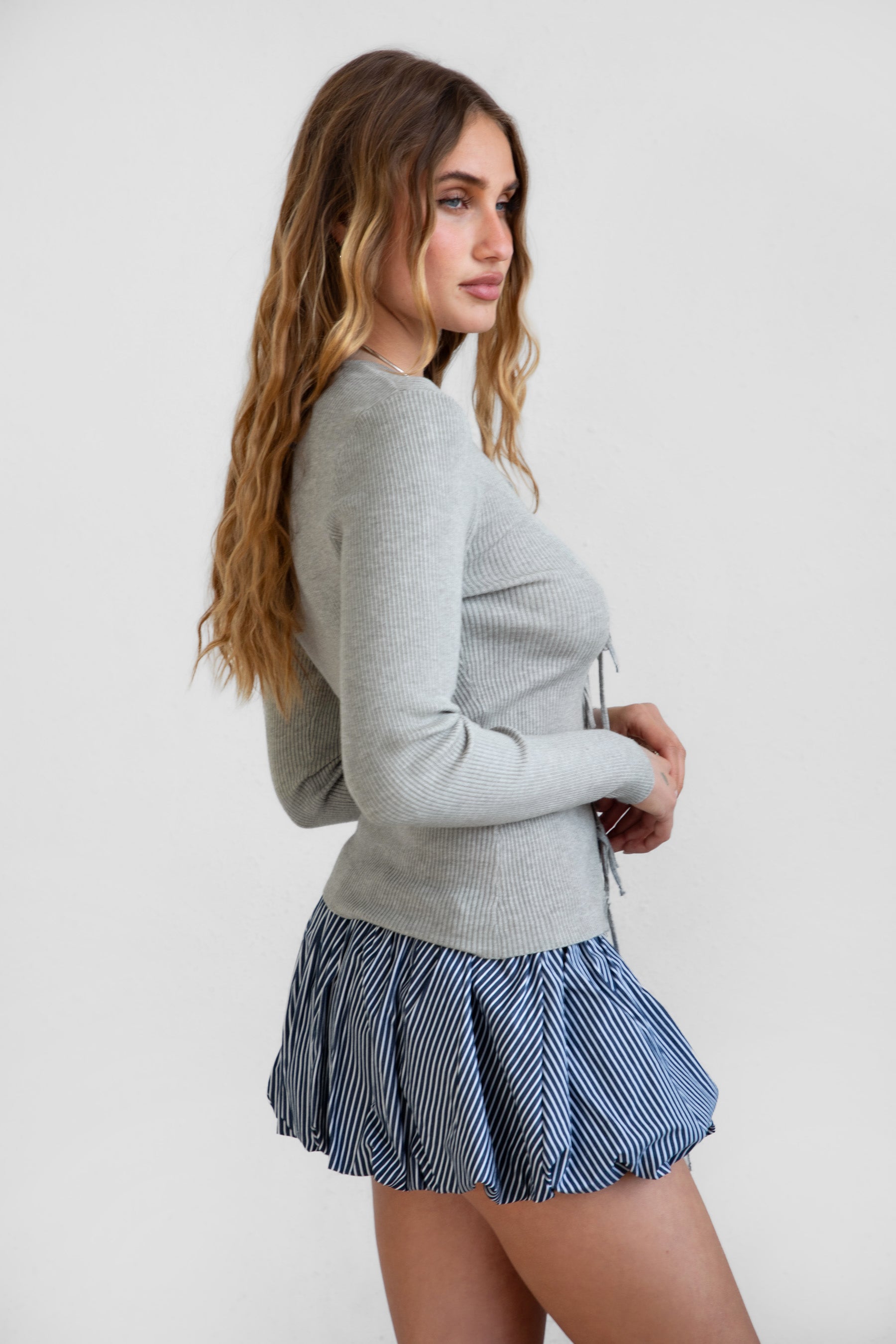 Woman wearing a gray sweater and blue checkered skirt on a white background