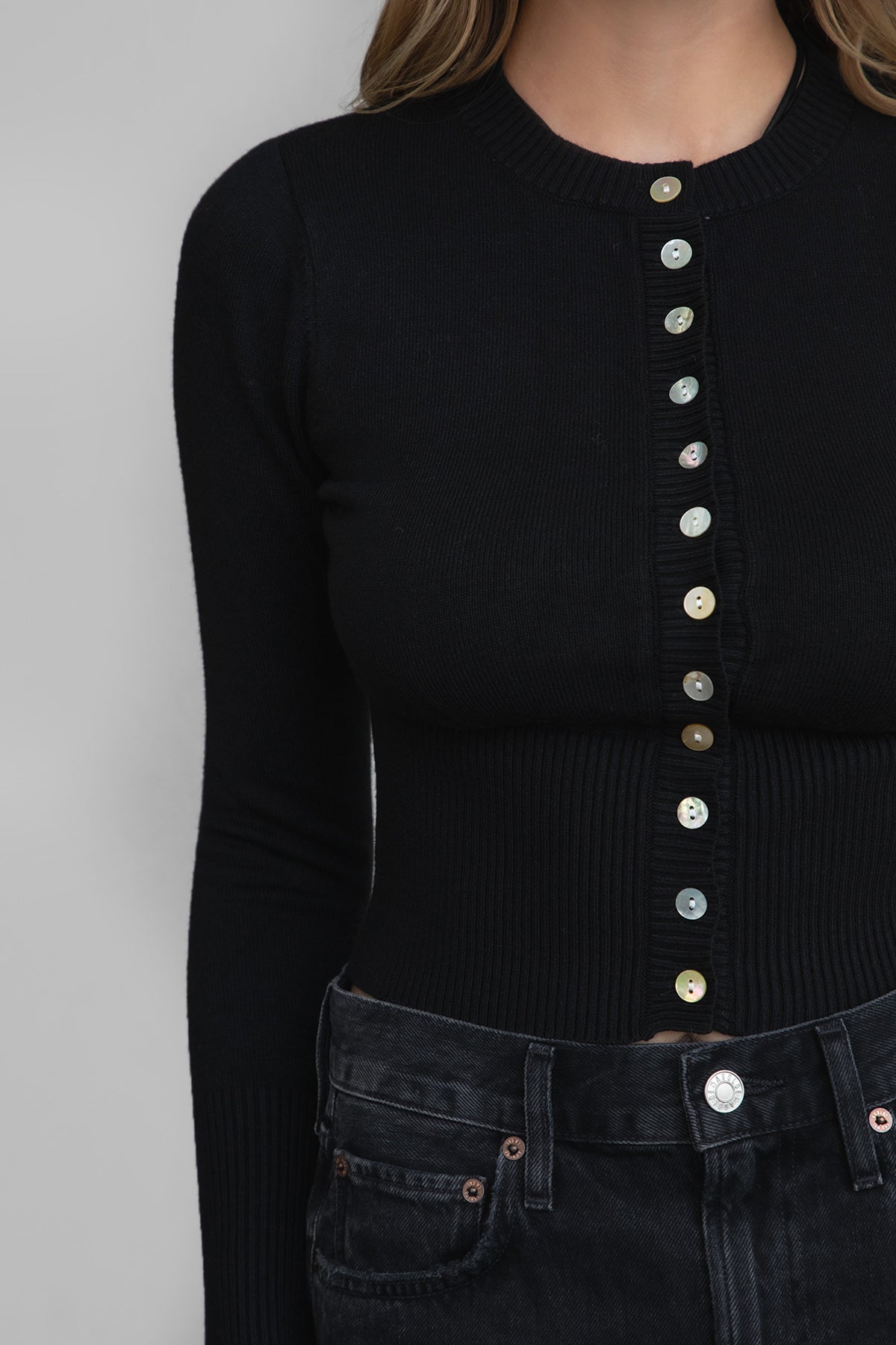 Woman wearing TIC TOC TC30563 OLIVEE knitted cardigan with button closure and fitted ribbed design in color black. 