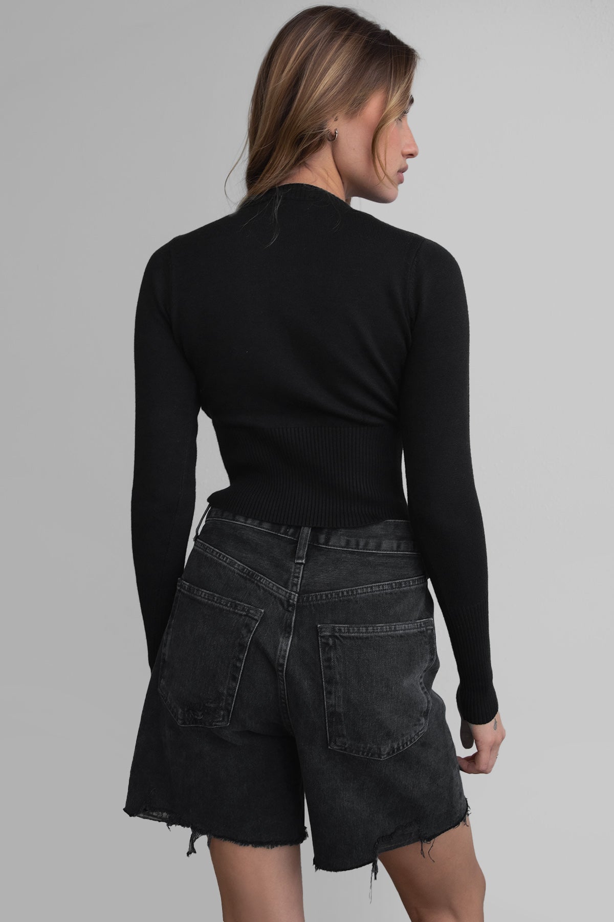Woman wearing TIC TOC TC30563 OLIVEE knitted cardigan with button closure and fitted ribbed design in color black. 