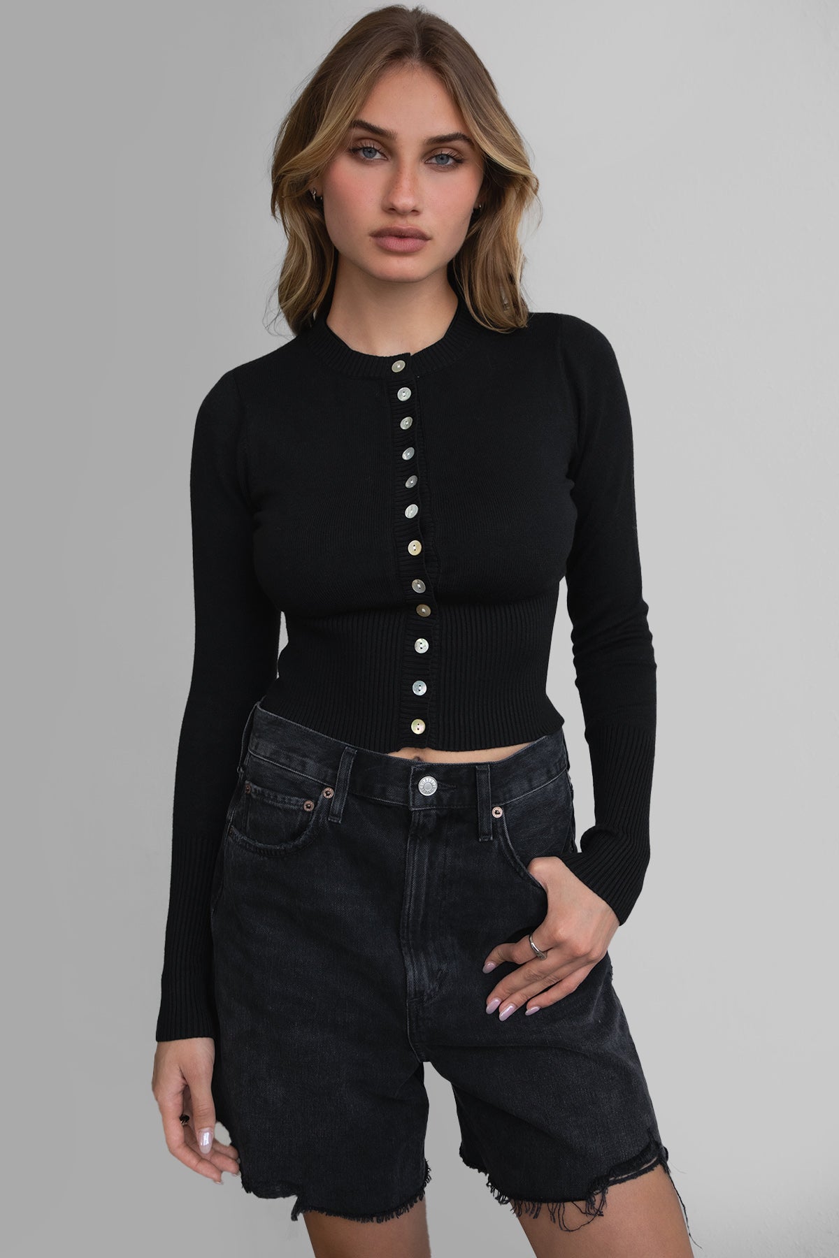 Woman wearing TIC TOC TC30563 OLIVEE knitted cardigan with button closure and fitted ribbed design in color black. 