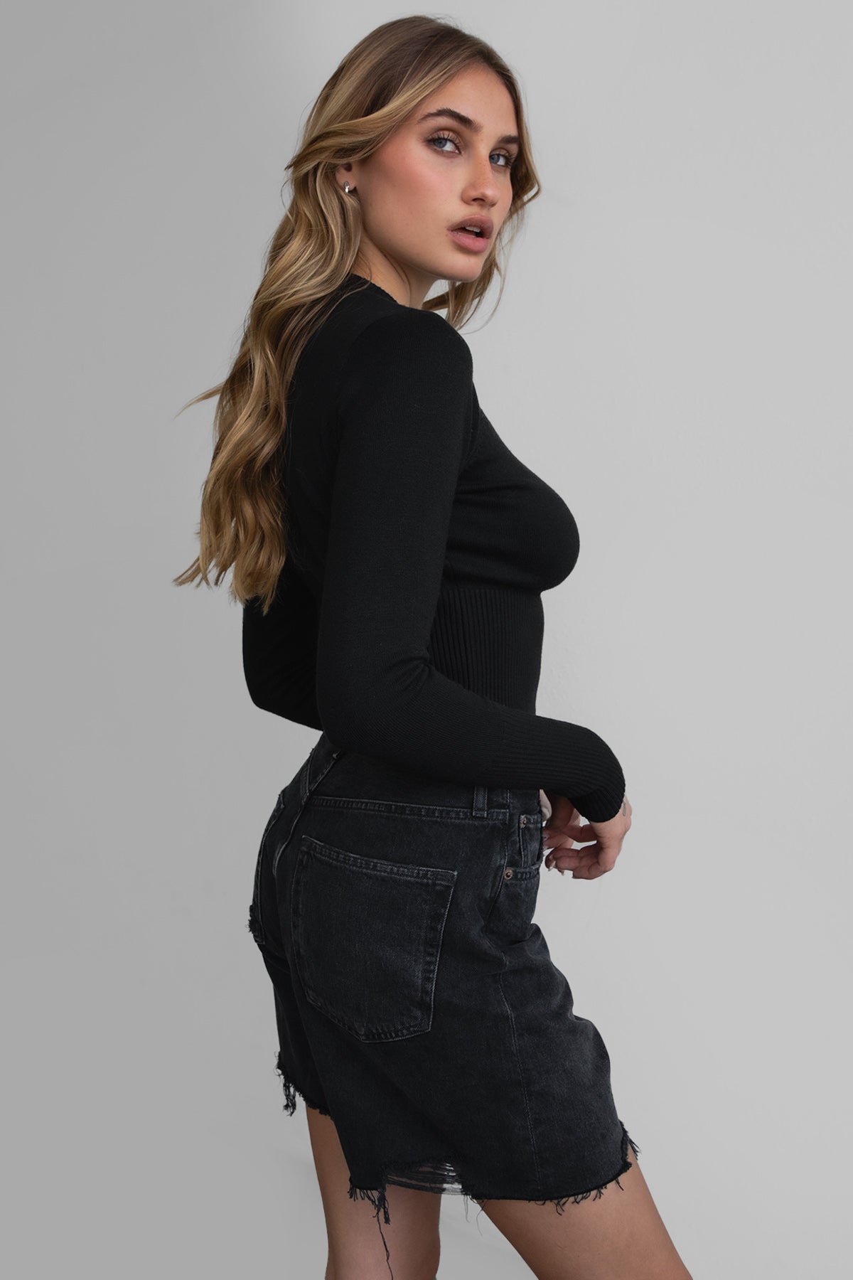 Woman wearing TIC TOC TC30563 OLIVEE knitted cardigan with button closure and fitted ribbed design in color black. 
