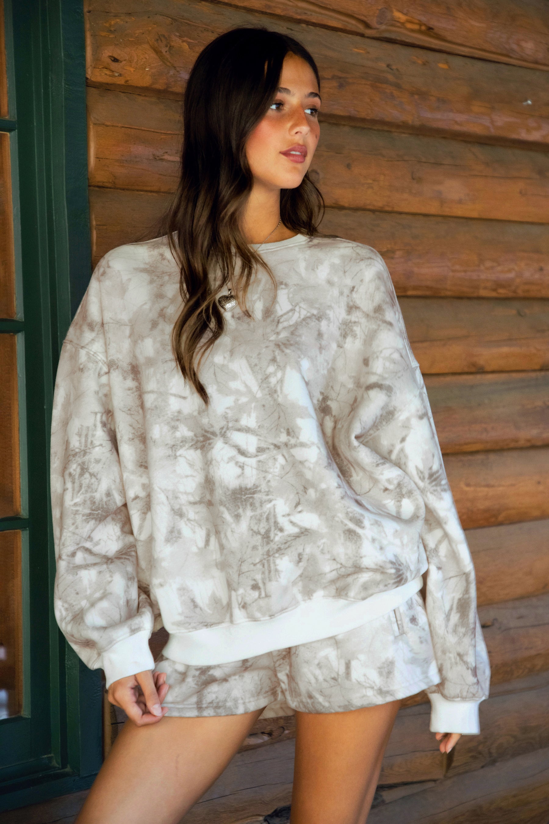 Person wearing a dusted woodland camo outfit standing on a wooden porch.