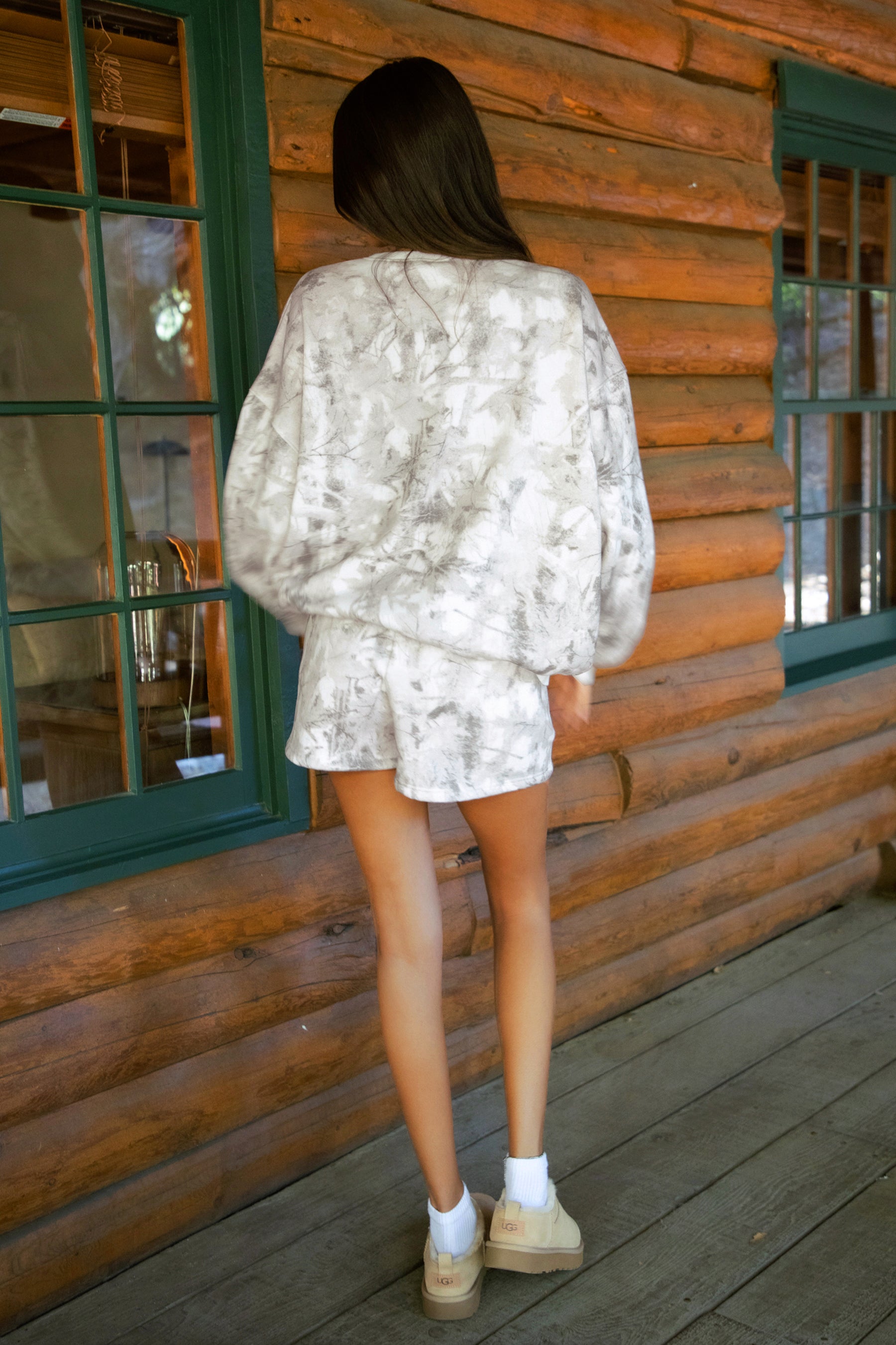 Person wearing a dusted woodland camo outfit standing on a wooden porch.