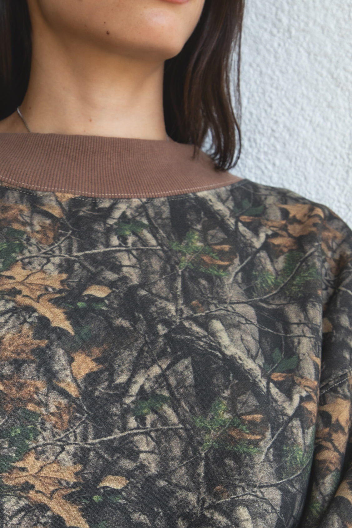 Woman wearing BAYOU dark woodland camo mock neck sweatshirt featuring soft cloud fleece fabric, allover woodland camo print, wide mock neckline with contrast ribbed trim, dropped shoulder relaxed silhouette, oversized fit, long sleeves, and contrast ribbed cuffs and hem.