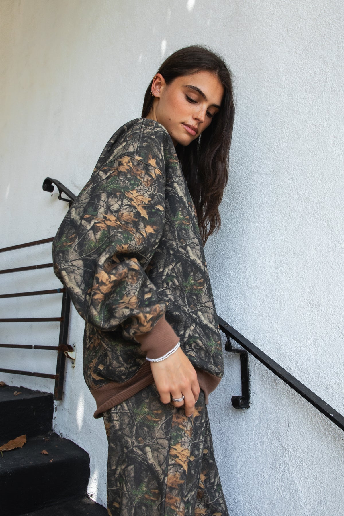 Woman wearing BAYOU dark woodland camo mock neck sweatshirt featuring soft cloud fleece fabric, allover woodland camo print, wide mock neckline with contrast ribbed trim, dropped shoulder relaxed silhouette, oversized fit, long sleeves, and contrast ribbed cuffs and hem.