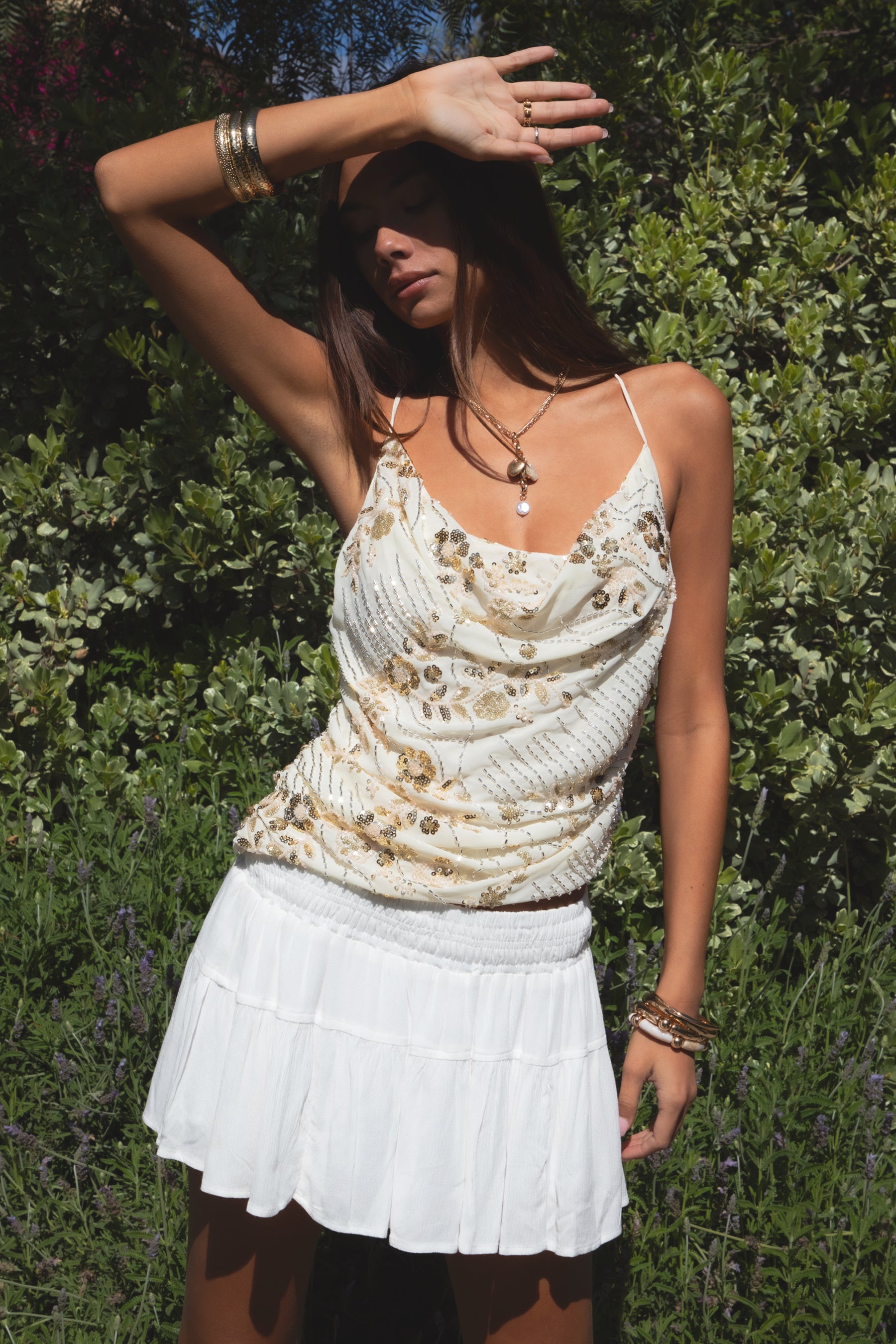 Woman wearing TIC TOC TL31684 AURYA chiffon sequin beaded cowl neck top featuring a draped cowl neckline, floral sequin and beaded embroidery, thin adjustable straps with cross back detail, fitted cropped silhouette, and asymmetrical hemline for a feminine festival and night-out look.