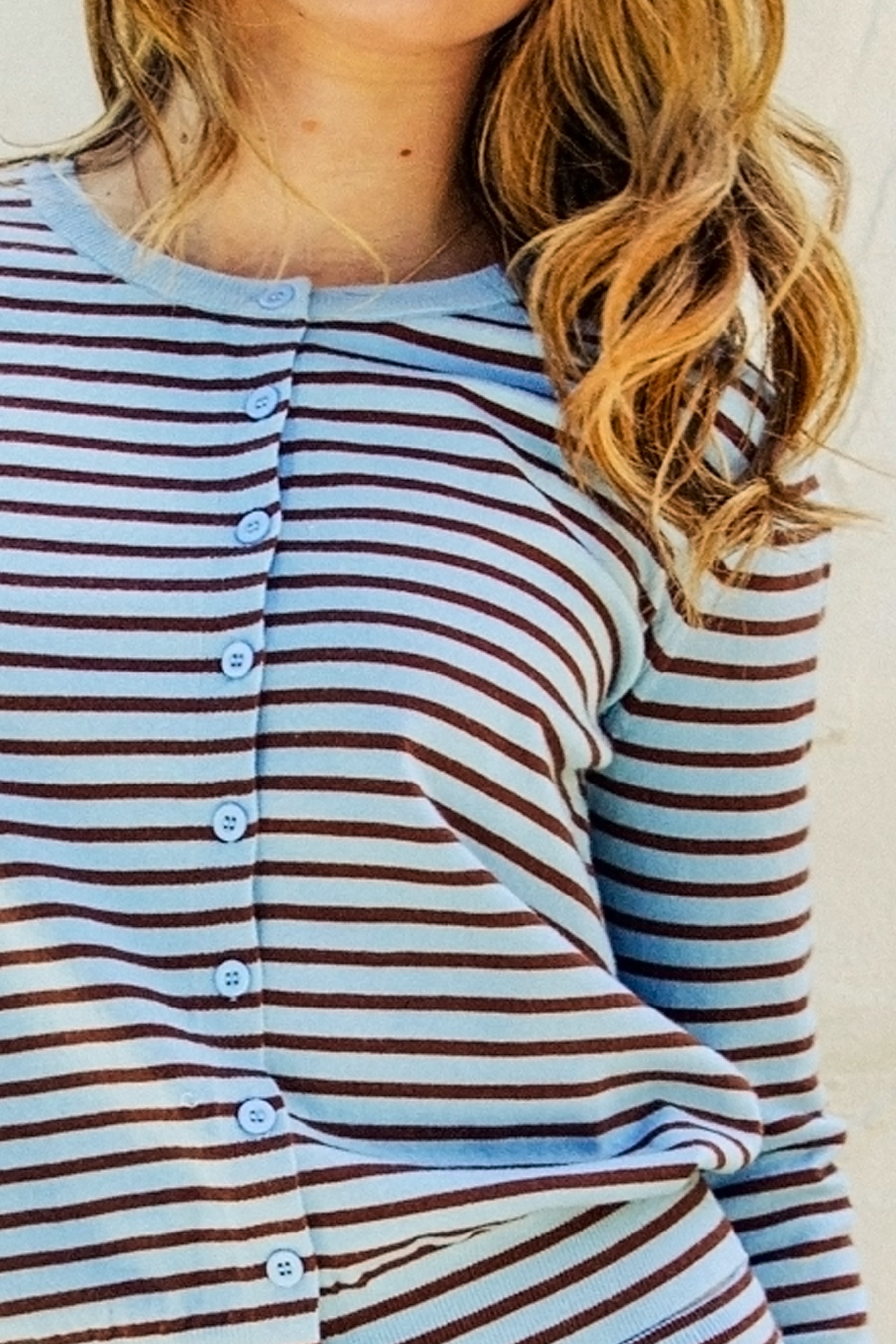 Woman wearing COVEE sweater knit stripe short and cardigan set featuring a classic stripe pattern, round neck cardigan with front button closure, soft stretch sweater knit fabric, and matching mid-rise micro shorts with ruched waist, elastic waistband, and adjustable drawstring.