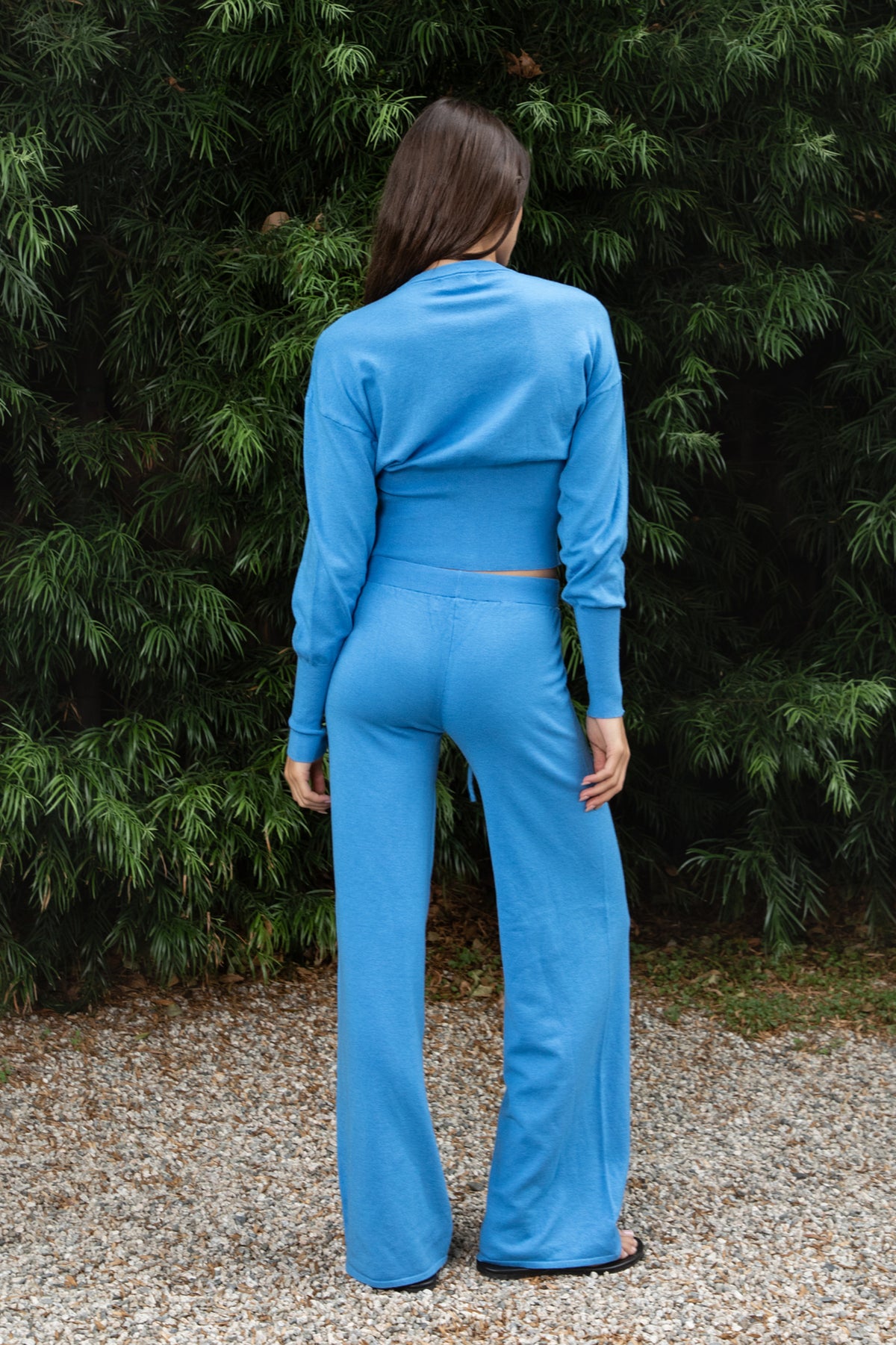 Woman wearing AZUREE button front cardigan and wide leg pants set featuring soft stretch sweater knit fabric, cropped cardigan with round neckline, covered button front closure, relaxed dropped shoulders, long sleeves with extended ribbed cuffs, fitted ribbed waistband, and matching high waisted pants with adjustable drawstring waist and relaxed full length wide leg silhouette.