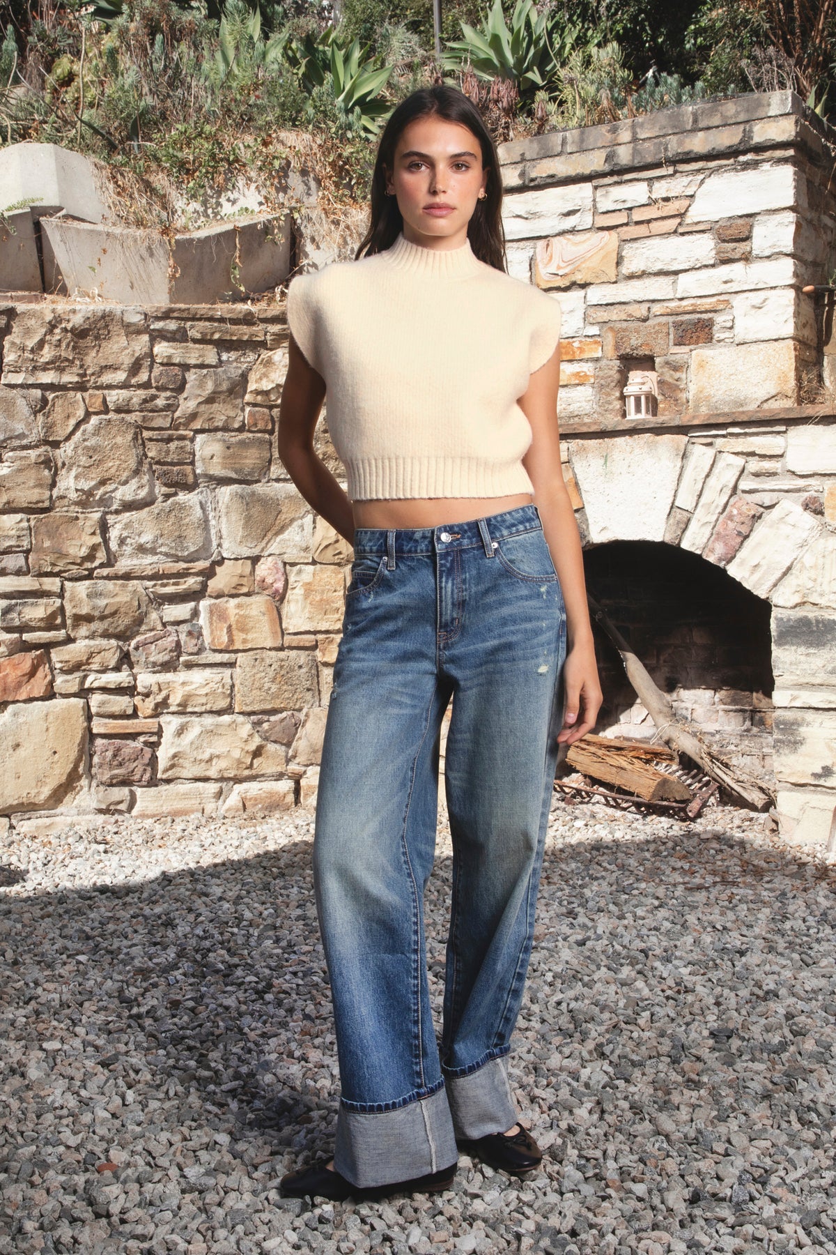 Woman wearing GARANCE mock neck sleeveless sweater top featuring a soft fuzzy knit texture, clean minimalist silhouette, polished mock neckline, relaxed bodice, subtle extended shoulder design, cropped length, wide ribbed hem, and solid color design for easy transitional layering.