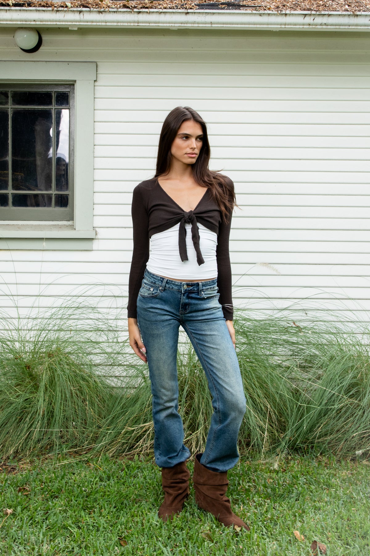 Woman wearing LUCIENNE front tie cropped bolero cardigan featuring soft lightweight cotton sweater knit fabric, deep V neckline, open front design, adjustable front tie closure at the bust, ultra cropped bolero silhouette, long fitted sleeves with ribbed cuffs, delicate knit trim along the neckline, and ribbed hem for a clean fitted finish.