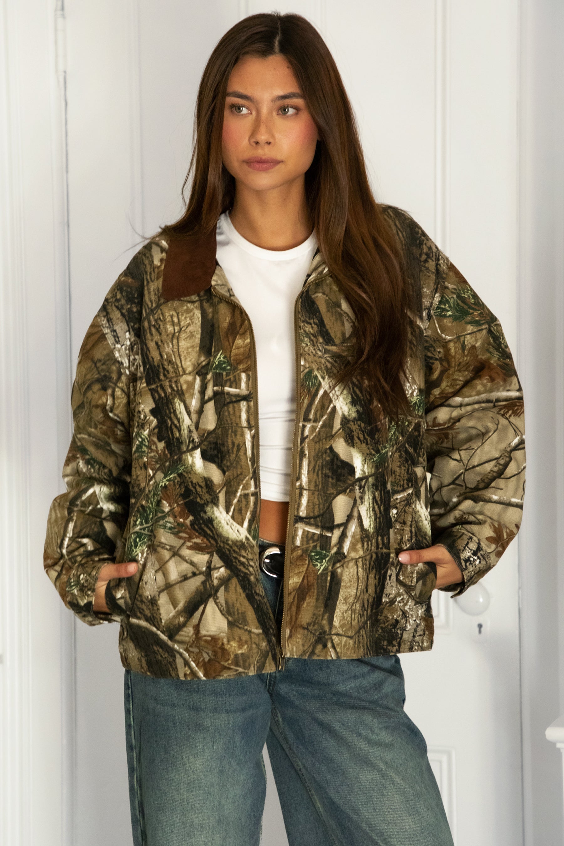 Woman wearing TIC TOC TT31858-LAUREL LAUREL oversized corduroy collar camo jacket featuring an allover wild camo print canvas twill body, contrast corduroy collar, front zipper closure, front two pockets, drop shoulder oversized fit, and satin quilted lining, styled with denim and a simple top for a western streetwear-inspired everyday look.
