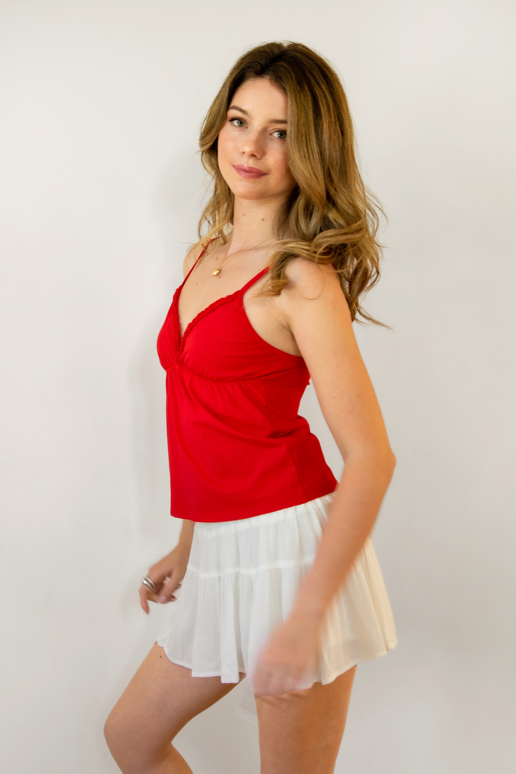 Woman wearing LEMONY cotton jersey lace trim cami top featuring a soft V-neckline with delicate ruffle trim, adjustable spaghetti straps, empire seam detail, and lightweight cotton jersey fabric with comfortable stretch for everyday layering and lounge styling.