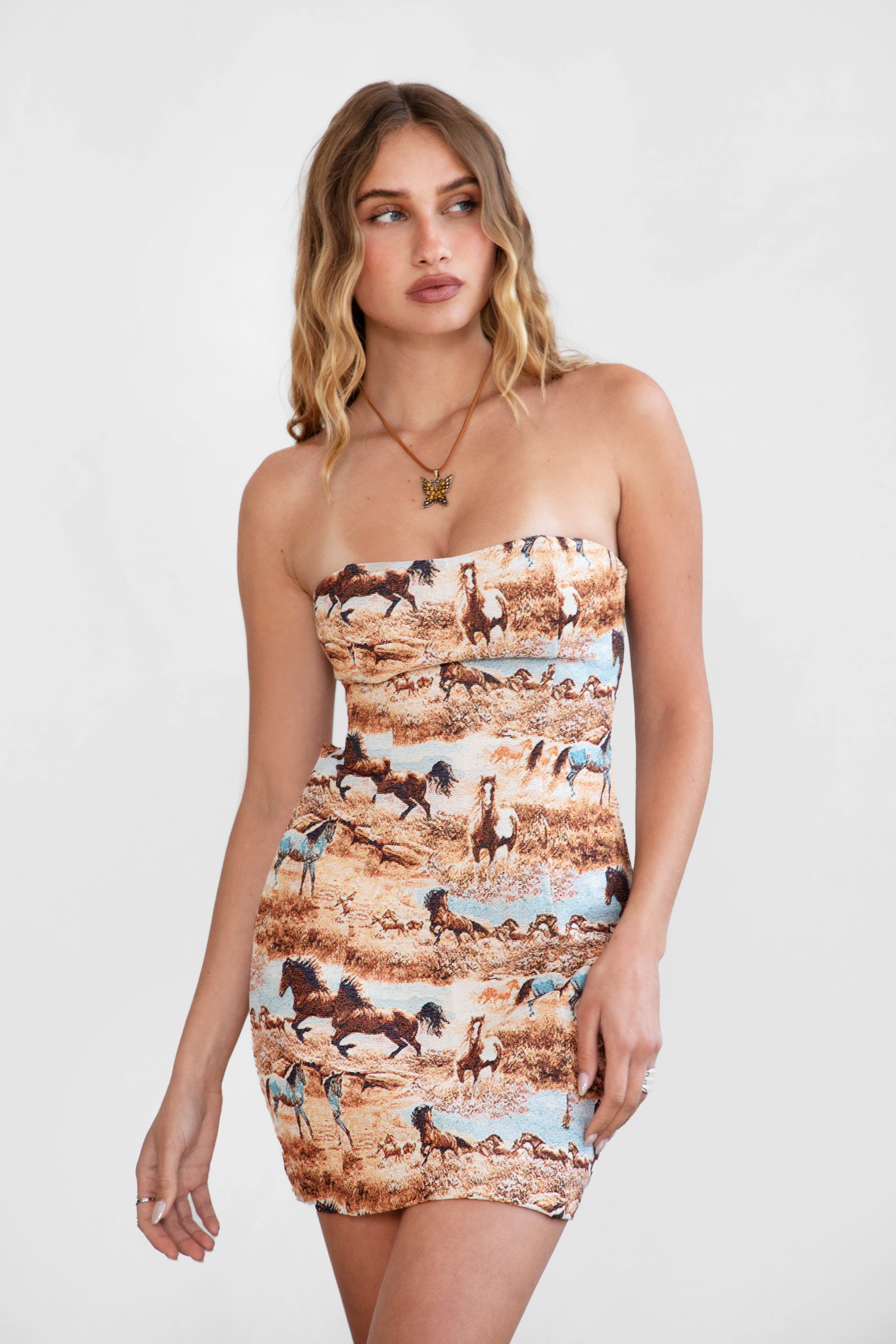 Woman wearing TIC TOC DA30763 DJANGO tapestry horse print strapless mini dress with lace-up back and open back cutout with cowboy boots. 