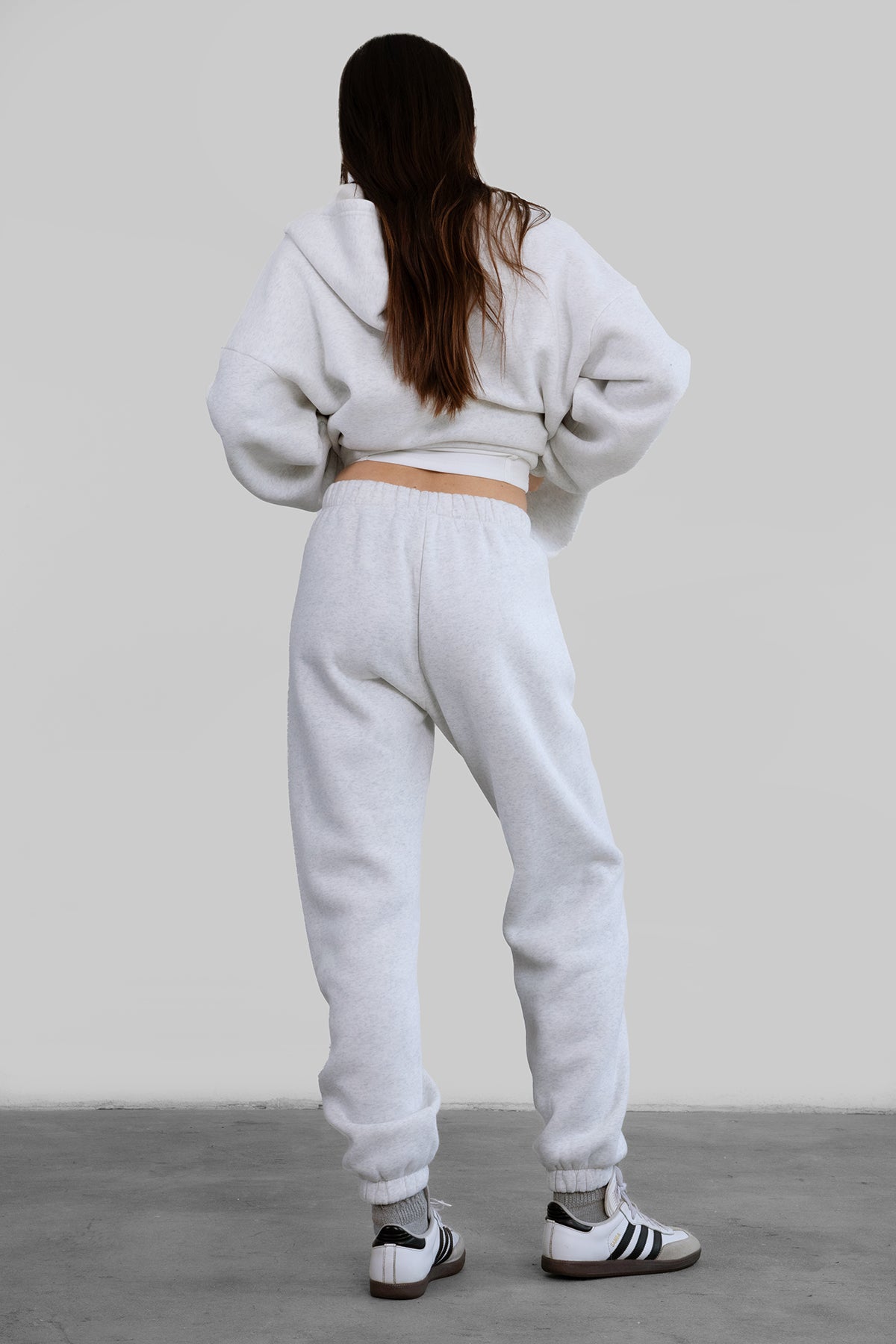 A pair of high-waisted, ash white sweatpants with an elasticated waistband, side pockets, and an ankle-length fit paired with maching top. 