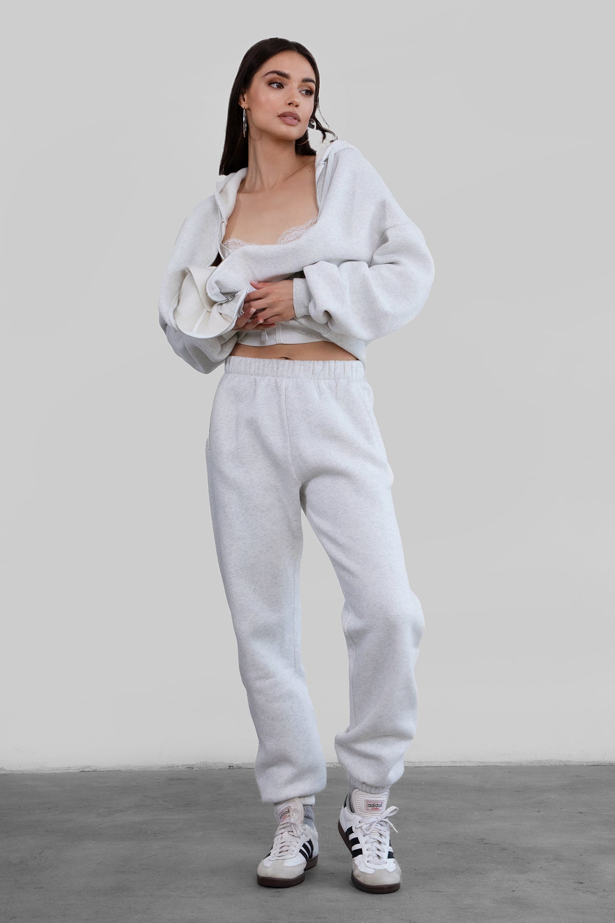 A pair of high-waisted, ash white sweatpants with an elasticated waistband, side pockets, and an ankle-length fit paired with maching top. 