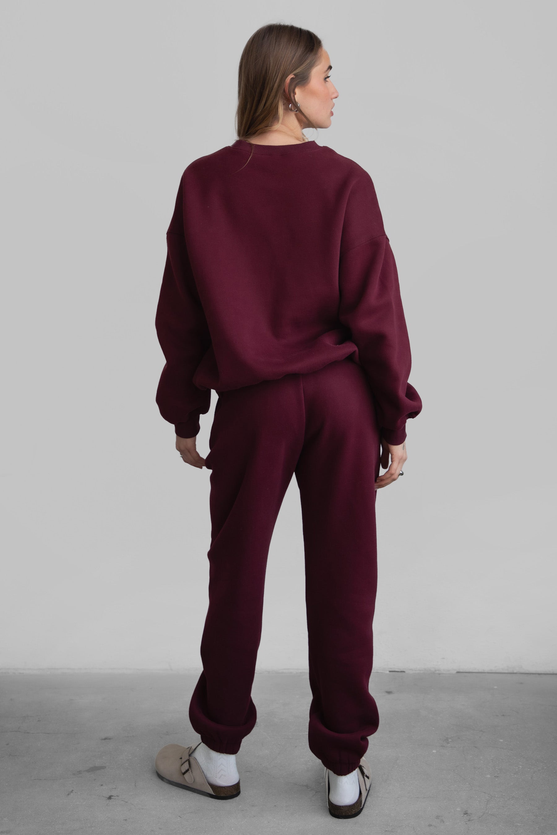 Woman wearing the TIC TOC PH26027 DOVE black cherry high waist sweatpants featuring an elastic waistband, deep side pockets, and tapered ankle hem with a matching top. 