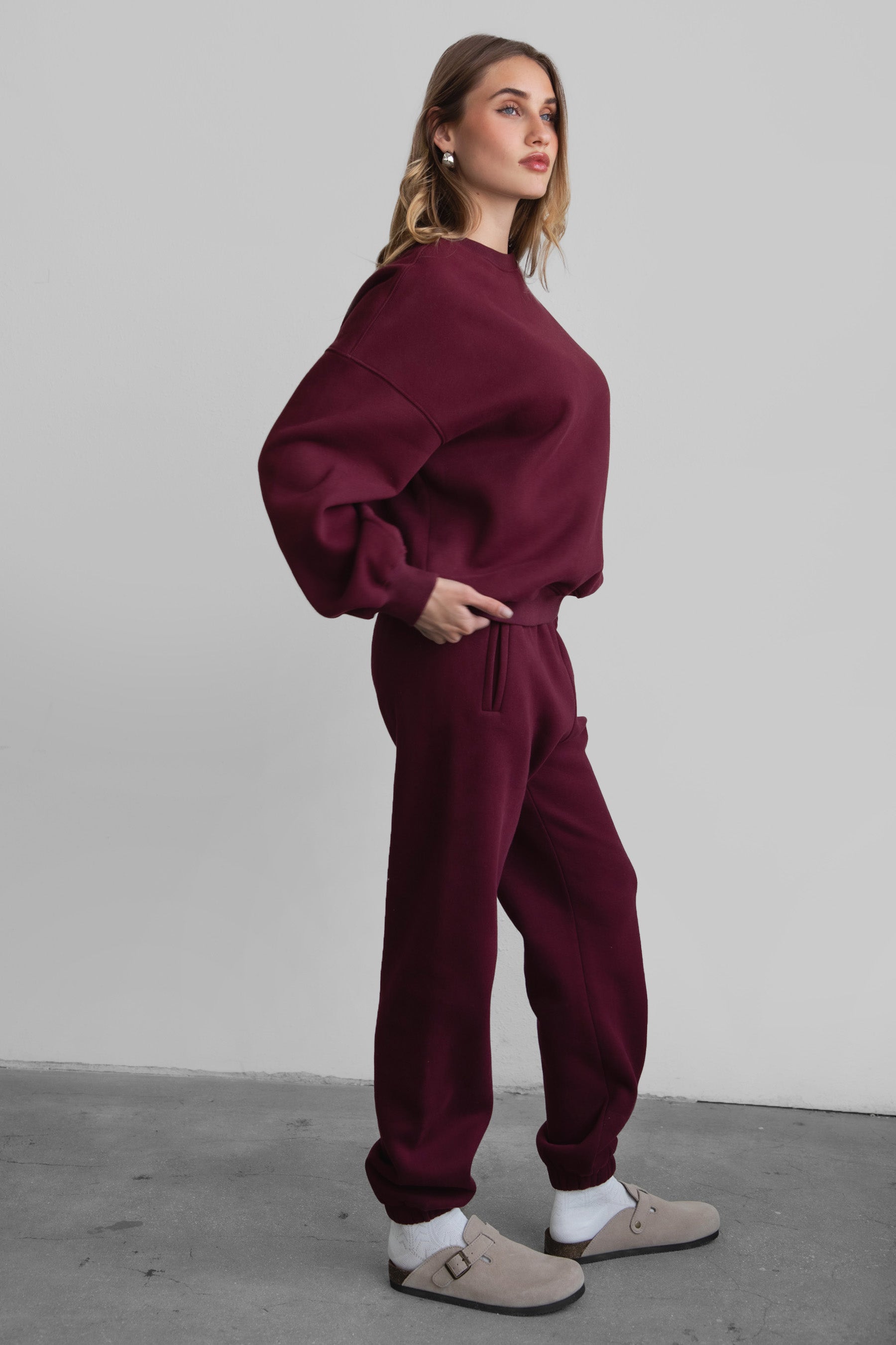 Woman wearing the TIC TOC PH26027 DOVE black cherry high waist sweatpants featuring an elastic waistband, deep side pockets, and tapered ankle hem with a matching top. 