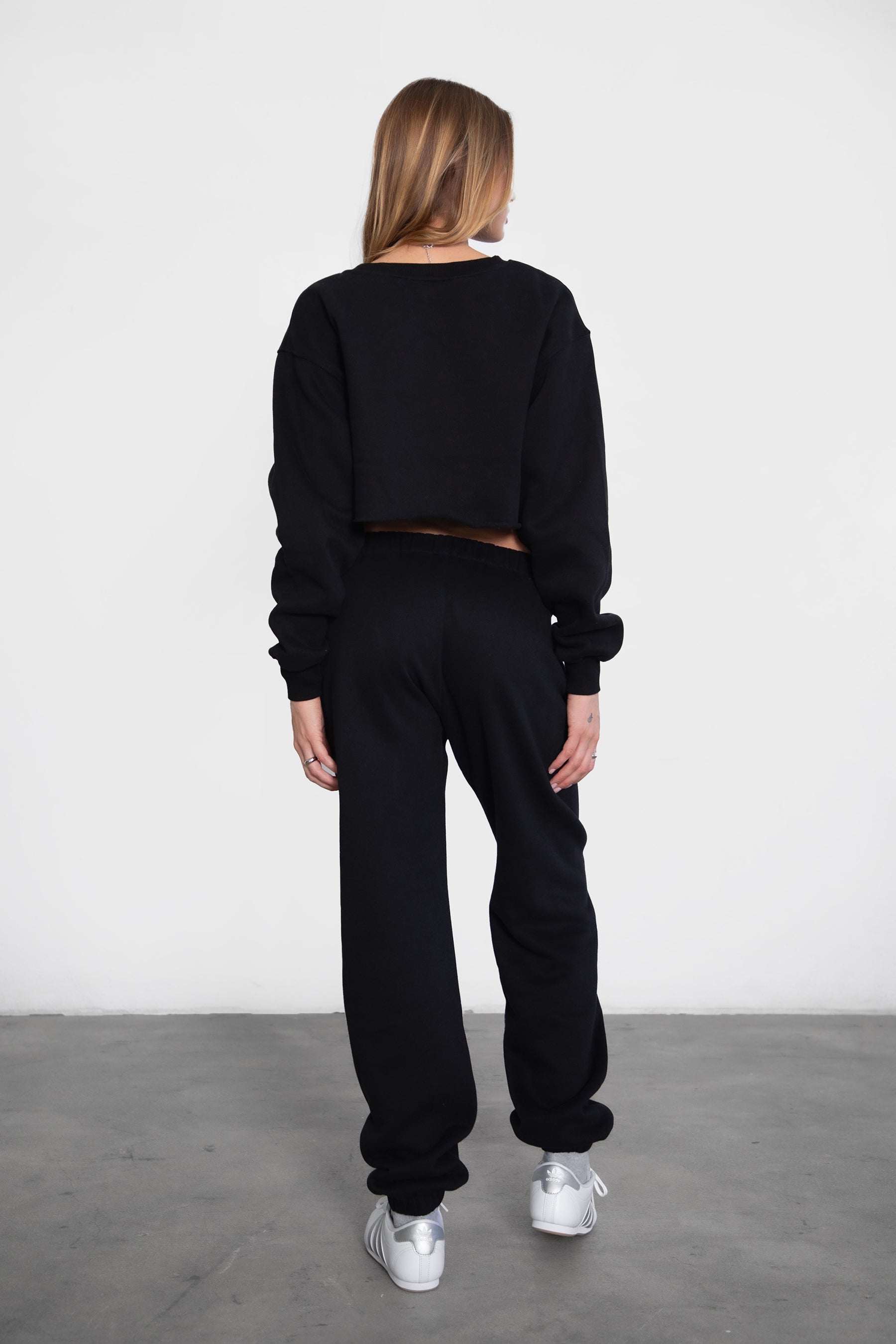 Woman wearing the TIC TOC PH26027 DOVE black high waist sweatpants featuring an elastic waistband, deep side pockets, and tapered ankle hem with a matching top. 