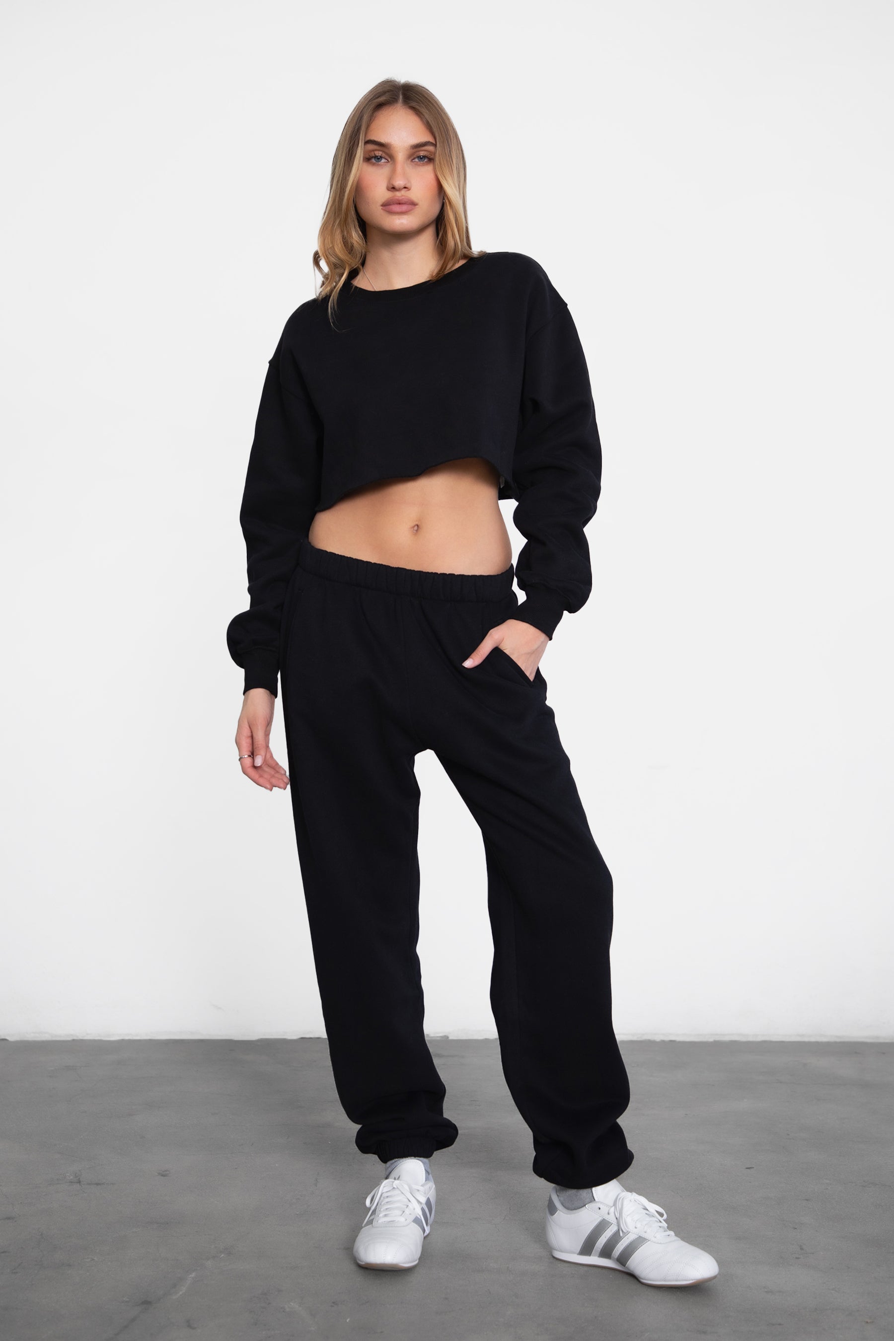 Woman wearing the TIC TOC PH26027 DOVE black high waist sweatpants featuring an elastic waistband, deep side pockets, and tapered ankle hem with a matching top. 