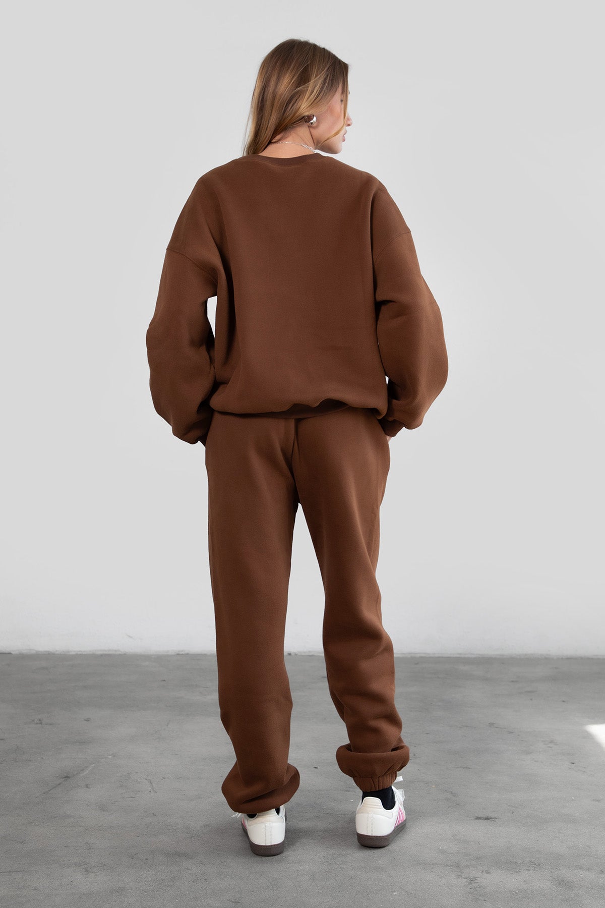 Woman wearing the TIC TOC PH26027 DOVE brown high waist sweatpants featuring an elastic waistband, deep side pockets, and tapered ankle hem with a matching top. 