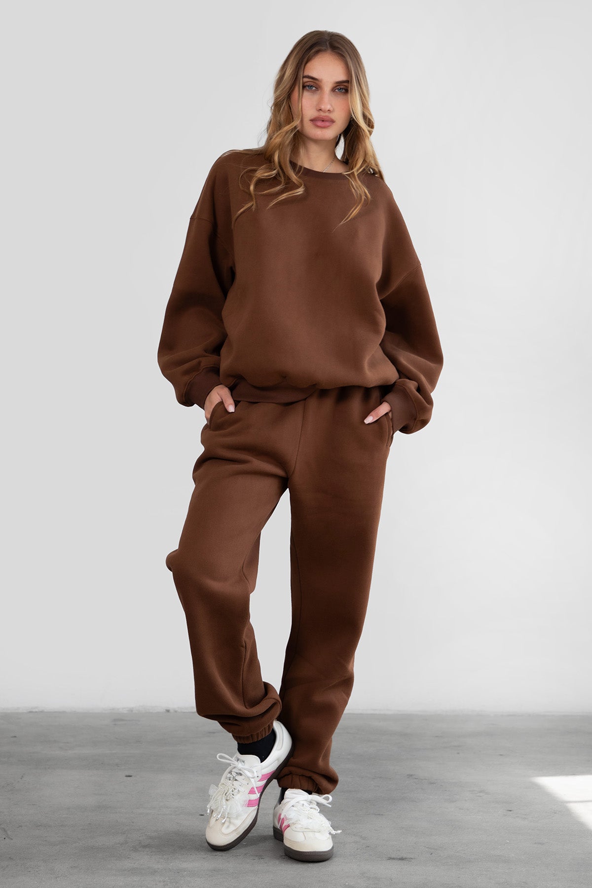 Woman wearing the TIC TOC PH26027 DOVE brown high waist sweatpants featuring an elastic waistband, deep side pockets, and tapered ankle hem with a matching top. 