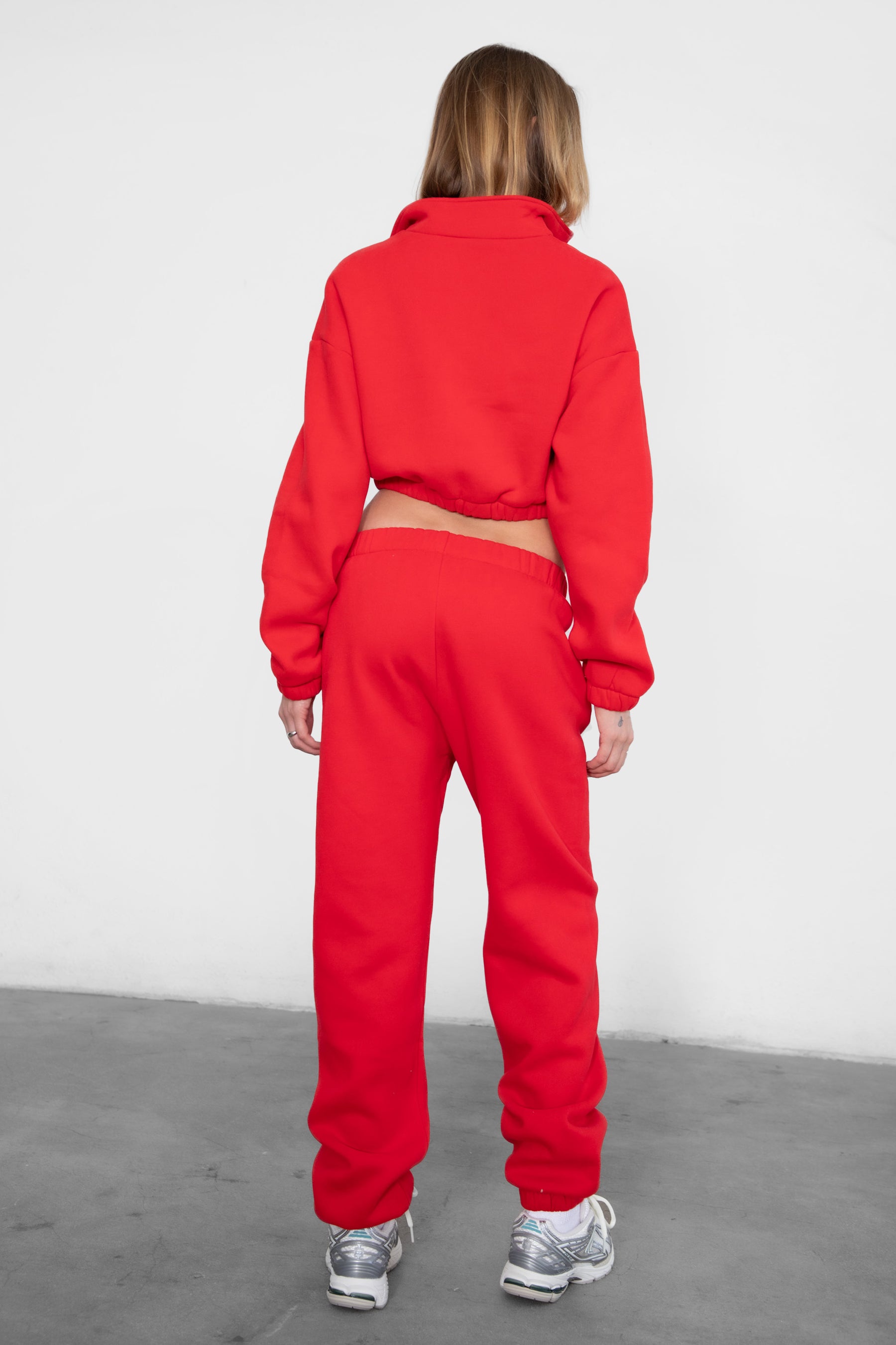 Woman wearing the TIC TOC PH26027 DOVE cherry red high waist sweatpants featuring an elastic waistband, deep side pockets, and tapered ankle hem with a matching top. 