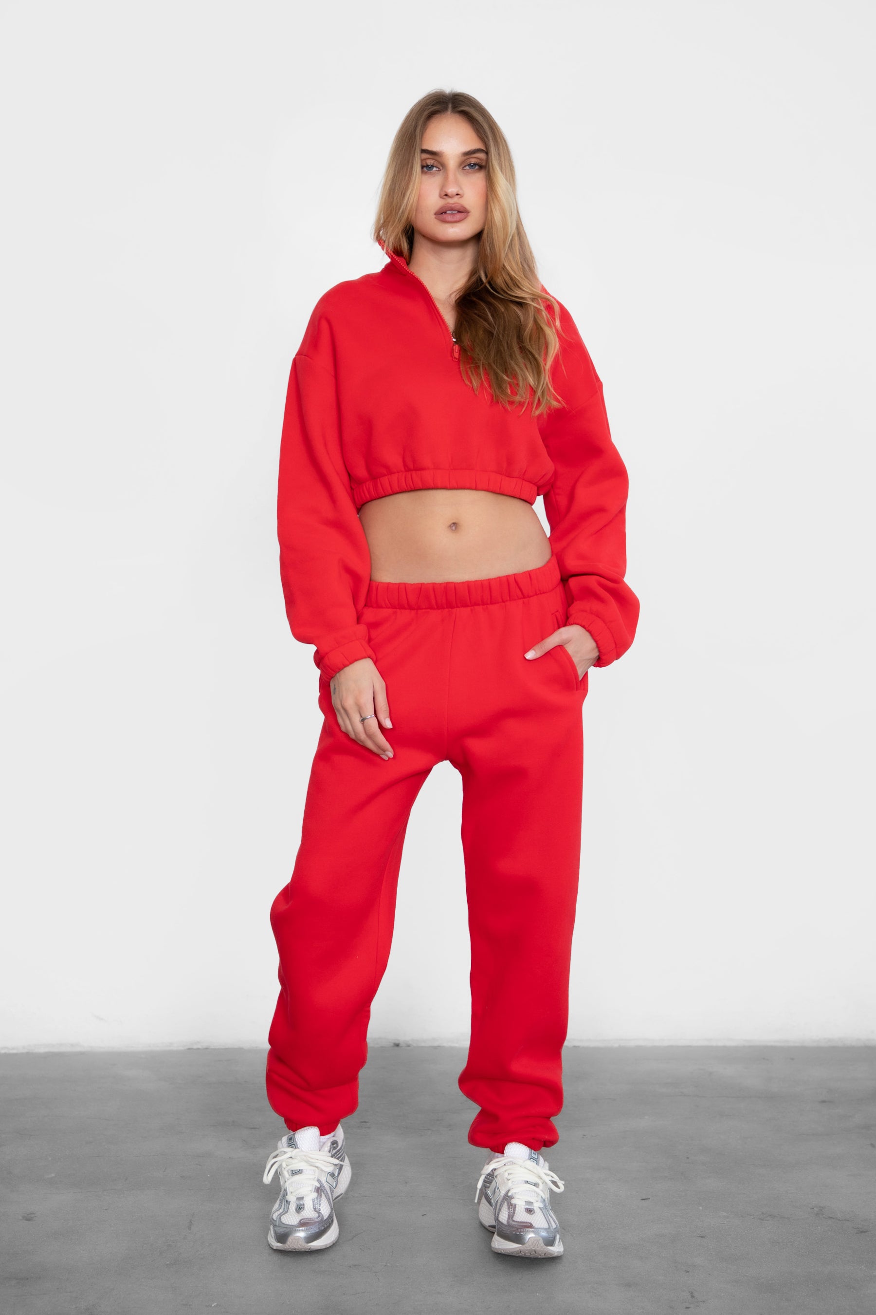 Woman wearing the TIC TOC PH26027 DOVE cherry red high waist sweatpants featuring an elastic waistband, deep side pockets, and tapered ankle hem with a matching top. 
