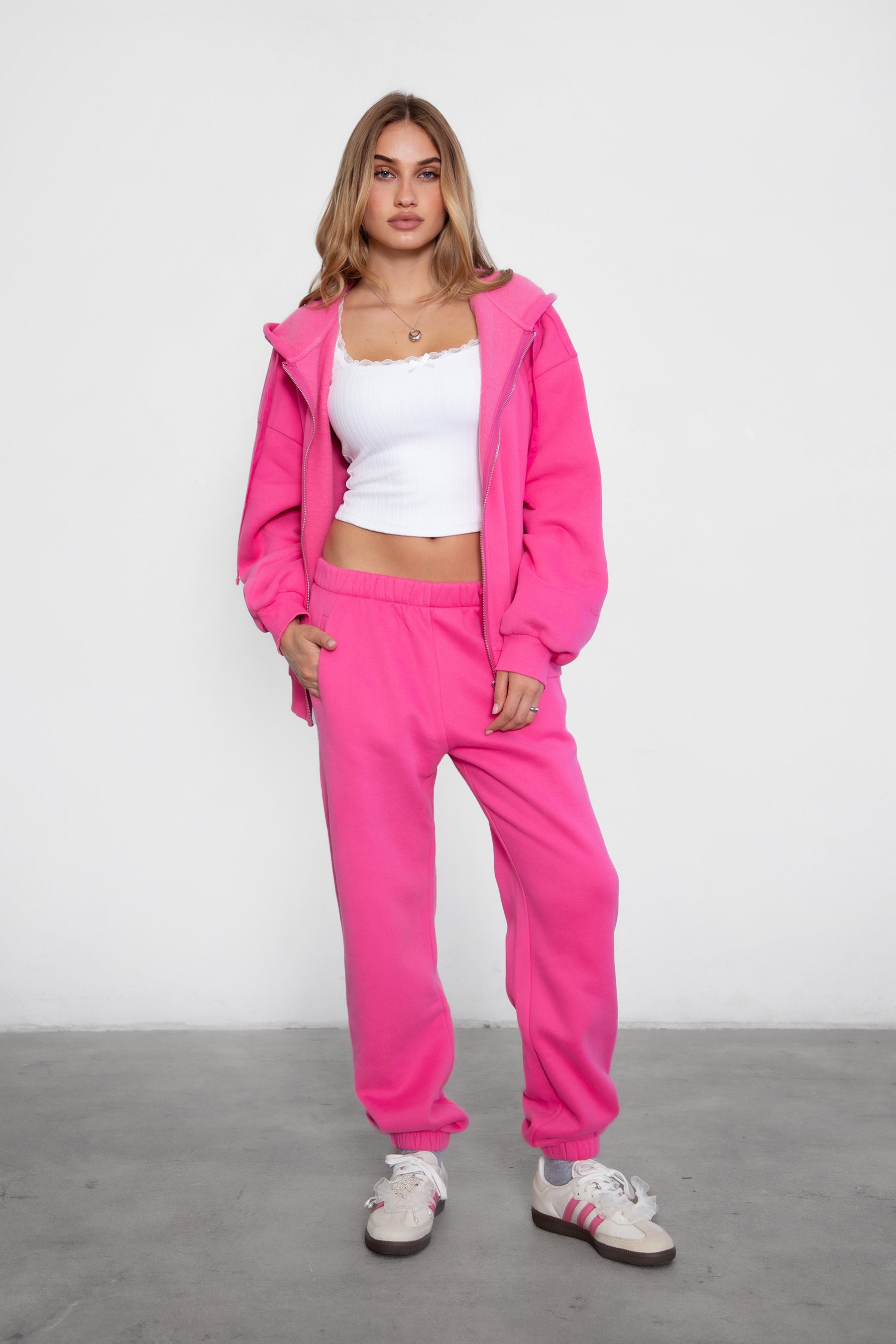 Woman wearing the TIC TOC PH26027 DOVE fuchsia high waist sweatpants featuring an elastic waistband, deep side pockets, and tapered ankle hem with a matching top. 