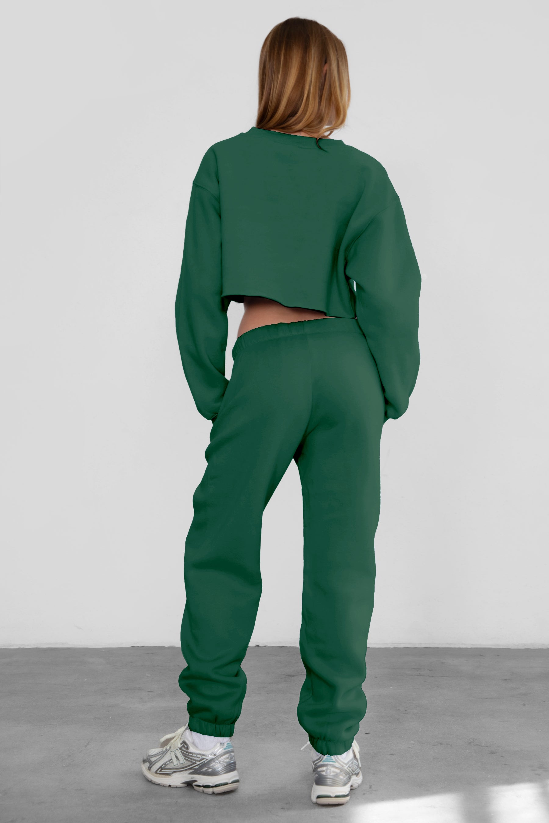 Woman wearing the TIC TOC PH26027 DOVE hunter green high waist sweatpants featuring an elastic waistband, deep side pockets, and tapered ankle hem with a matching top. 